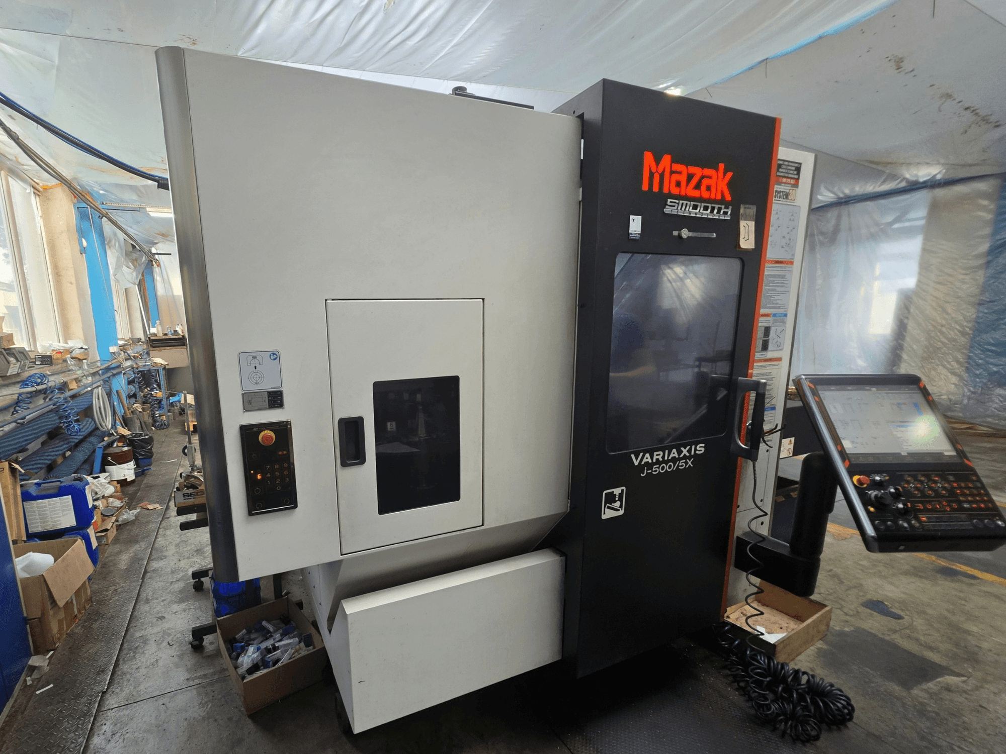 Mazak VARIAXIS J-500/5X vertikalt bearbetningscenter, sidovy som visar manöverelement och display, placerat i en verkstadsmiljö.