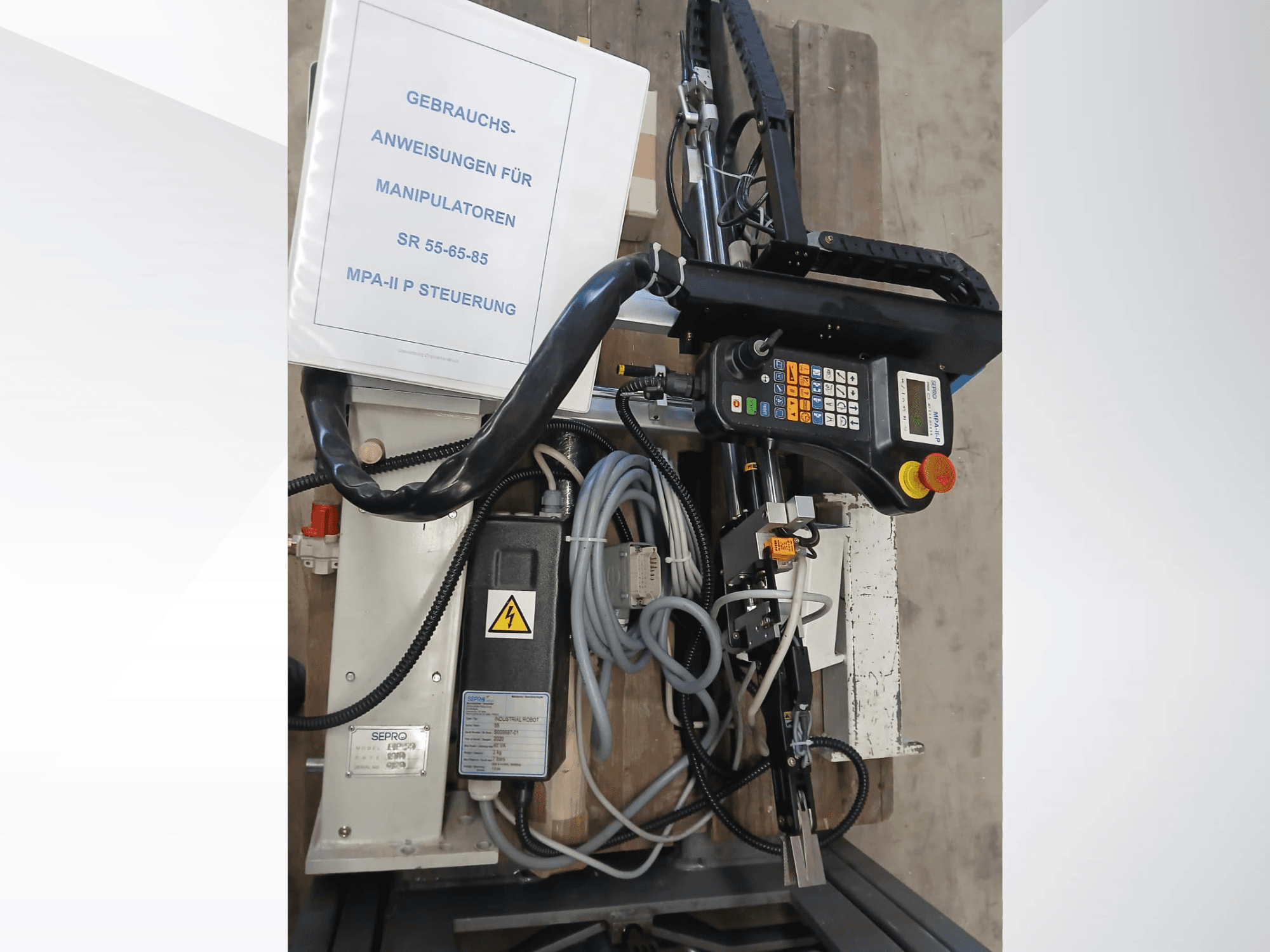 Sepro PIP-55 Gantry Robot kontrollpanel och komponenter, sett från sidan, med användarmanual synlig.