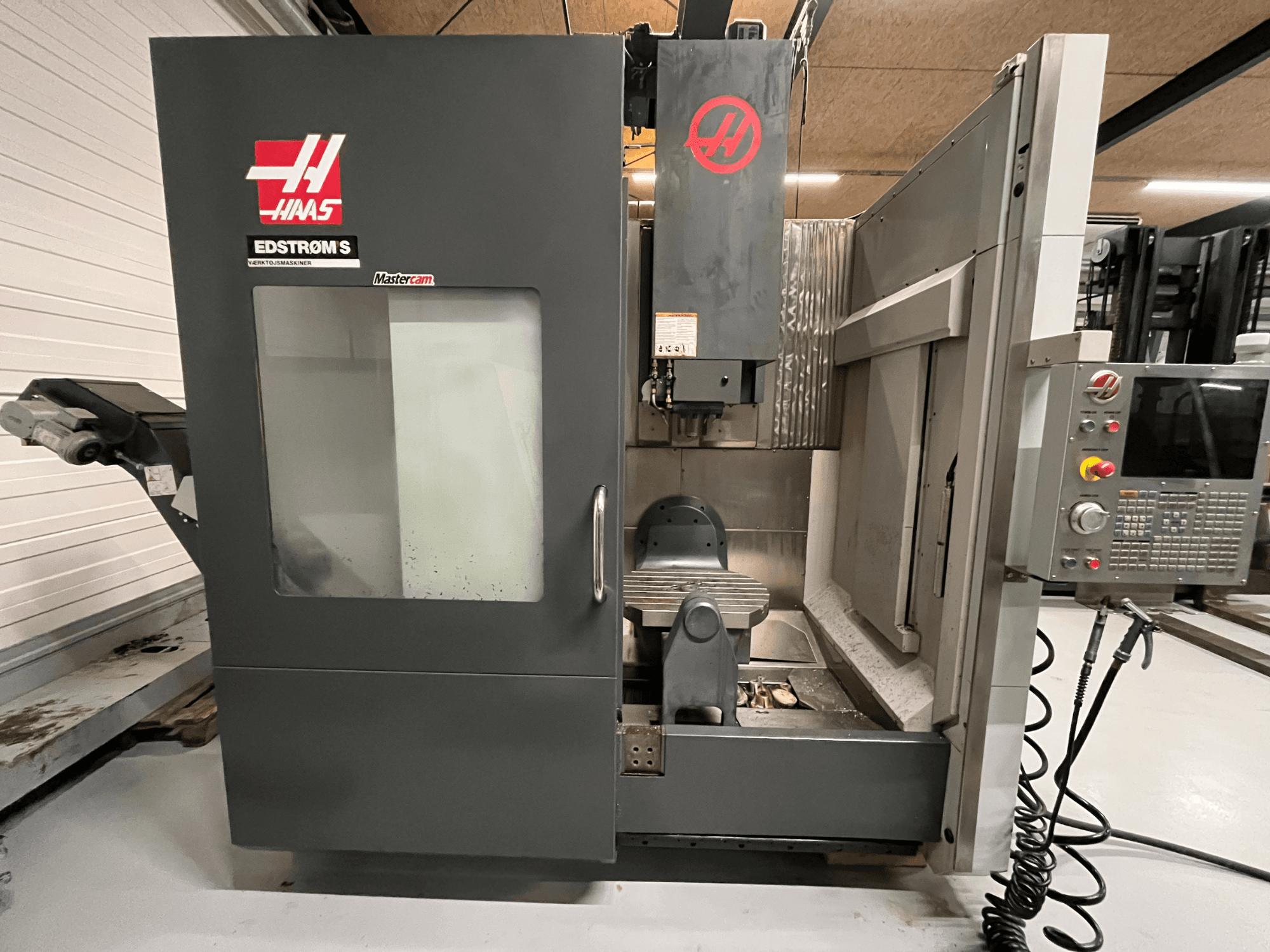 Haas EDSTROM S CNC-maskin framifrån visar kontrollpanelen, spindelhuvudet och bearbetningsbordet.