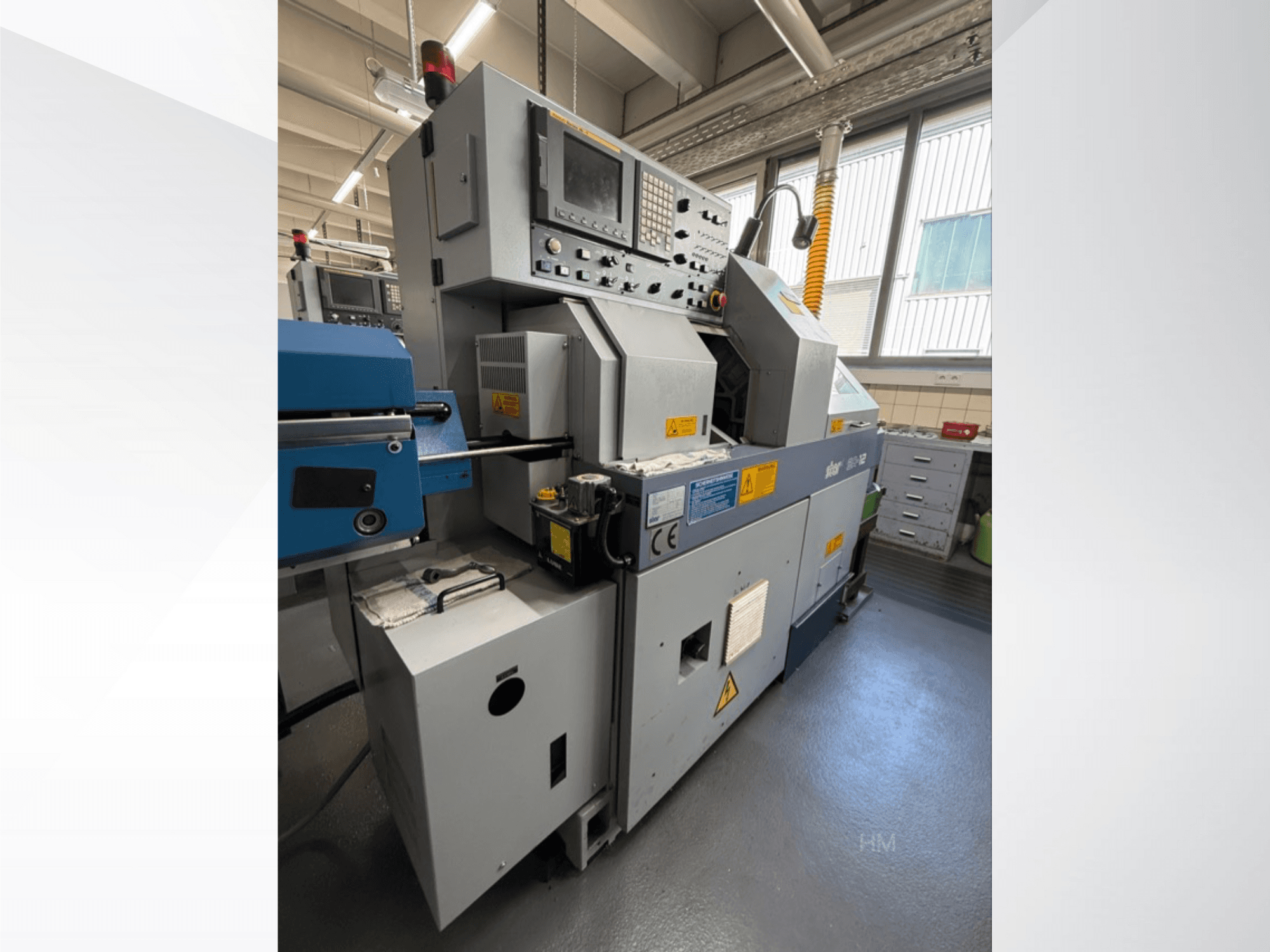 Framsidan av maskinen Lithec 3231, som visar kontrollpanelen, motorn och den blå matningssektionen i en väl upplyst industrimiljö.