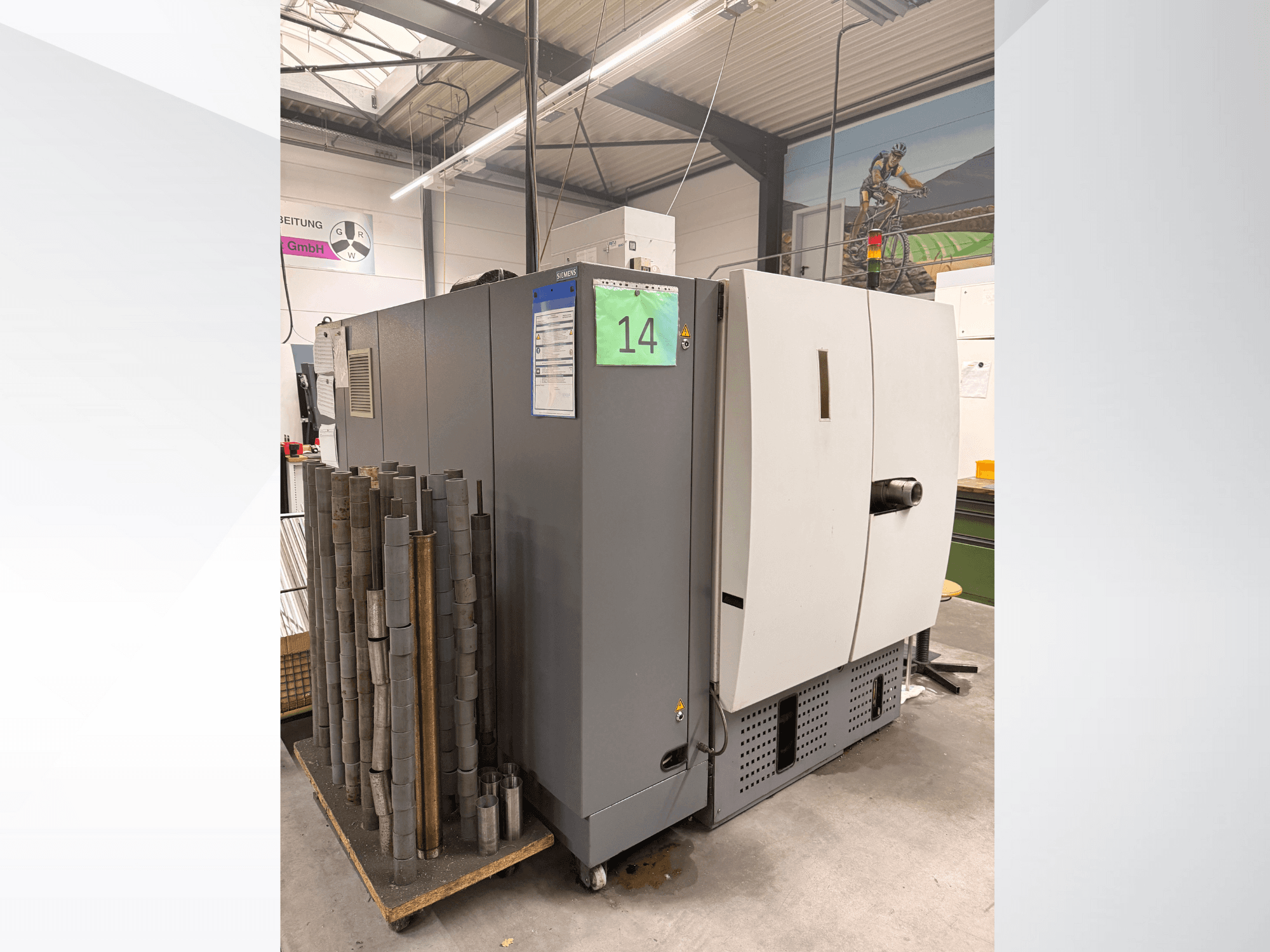 Grå industrimaskin från Siemens, vy från sidan, med lager av cylindriska metalldelar bredvid och synliga utrustningsetiketter.