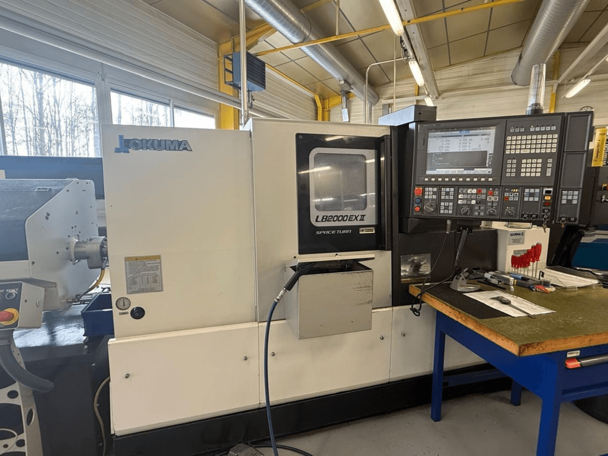 Okuma LB2000EX II horisontell svarv, vy framifrån; med kontrollpanel, spindelområde och omgivande arbetsyta.