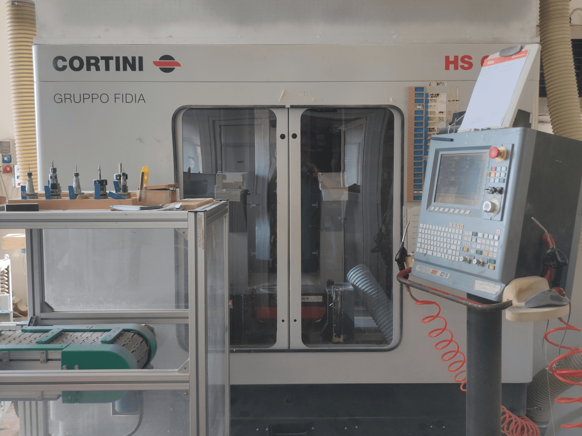 CORTINI HS 644 vertikal bearbetningscenter framifrån, med kontrollpanel, verktyg på displayen och synliga maskinkomponenter.