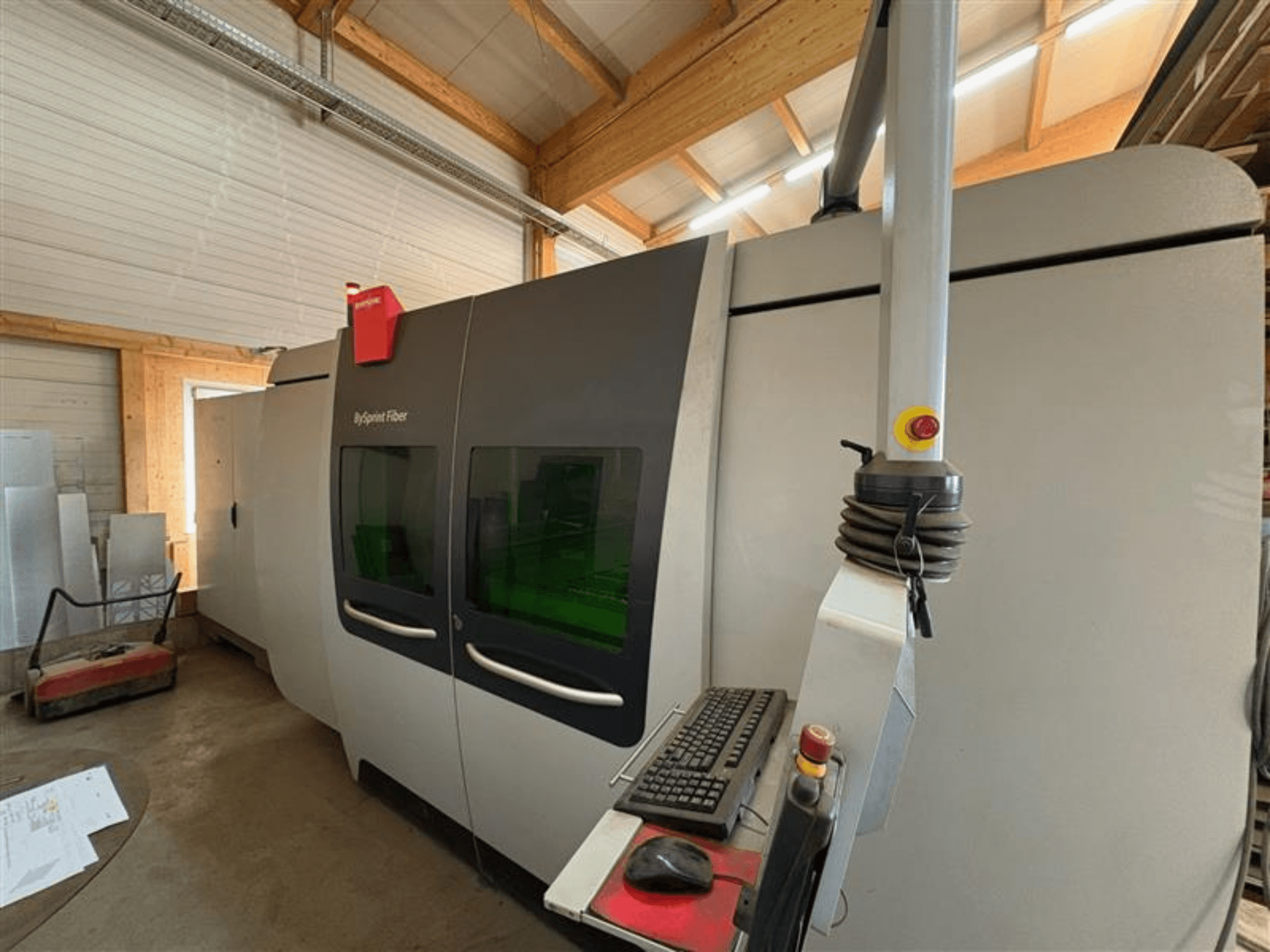 Bystronic ByJet Fiberskärmaskin i en verkstad, framifrån med kontrollpanel och dubbla gröna visningsfönster.