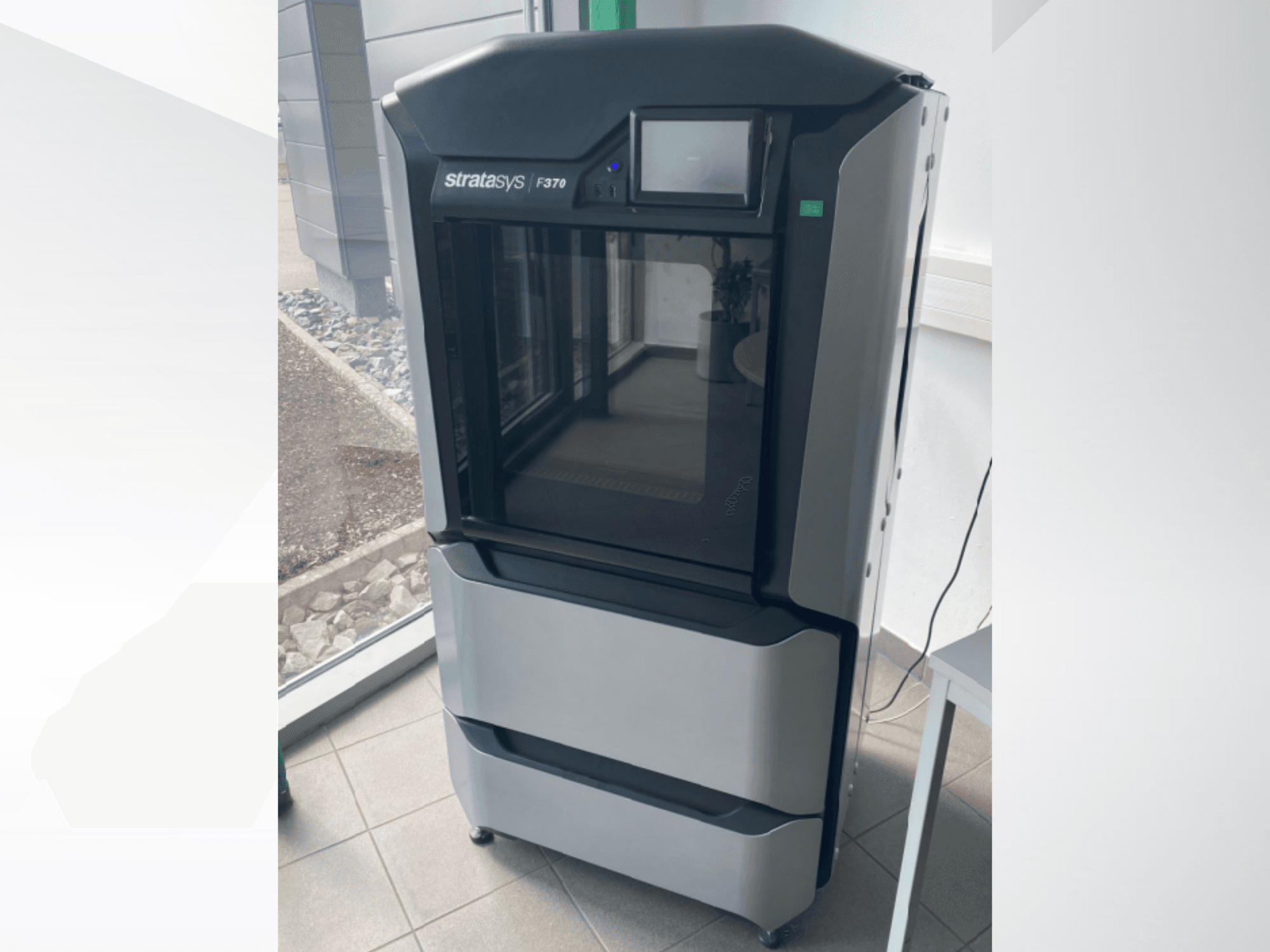 Stratasys F370 3D-skrivare för plast, framifrån, visar en elegant svart och grå design med en pekskärm.