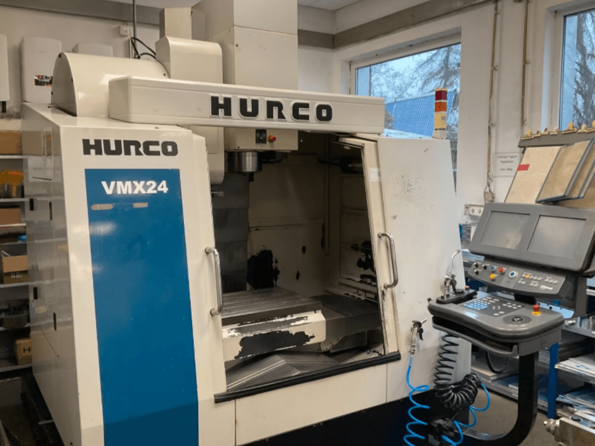 Hurco VMX24 vertikalt bearbetningscenter sett framifrån, med kontrollpanelen, spindelhuvudet och arbetsområdet synliga, samt vissa tecken på slitage.