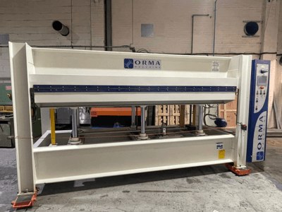 Hydraulisk press från ORMA-maskiner, framifrån, med silverfärgad yta, kontrollpanel till höger och stående kolvar för pressning.