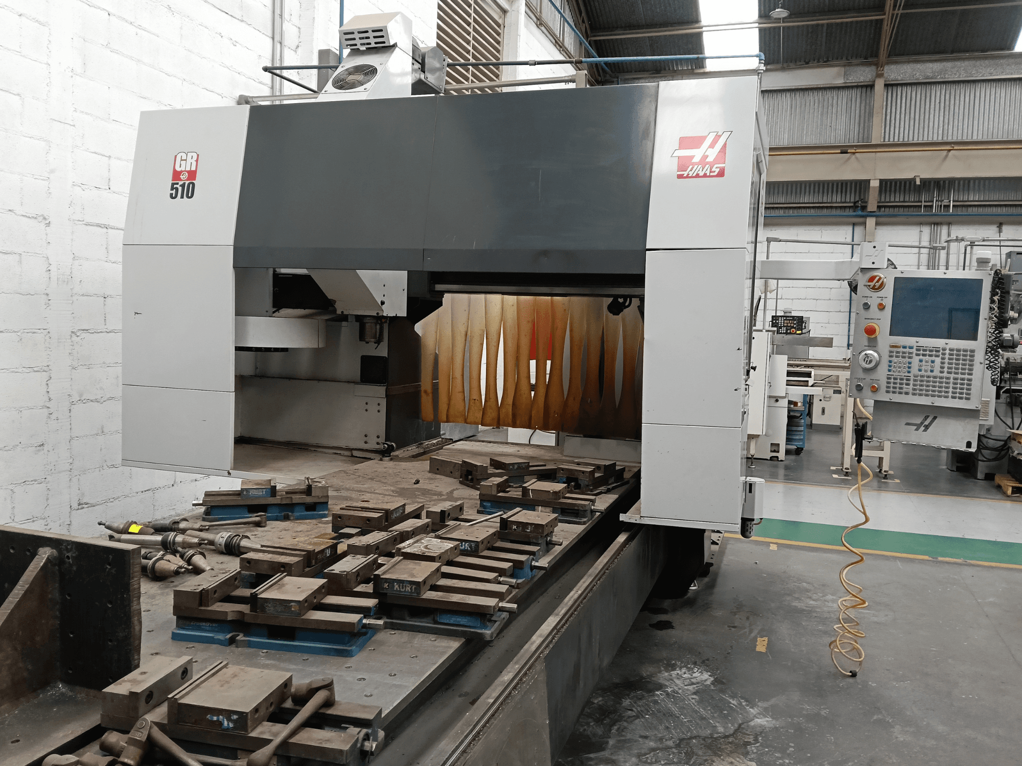 Framifrånvy av portfräsmaskinen HAAS GR-510, där man ser kontrollpanelen och de bearbetade arbetsstyckena på bordet.