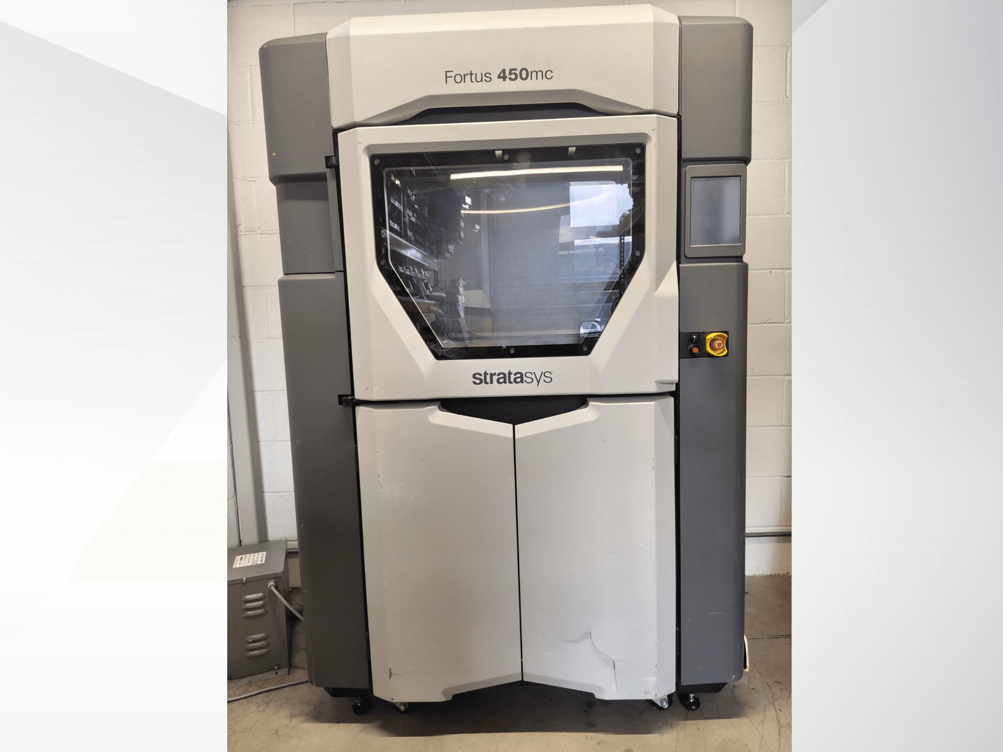 Stratasys Fortus 450mc plastbearbetningsmaskin, framifrån, med ett stort fönster, kontrollpanel och industriell design.
