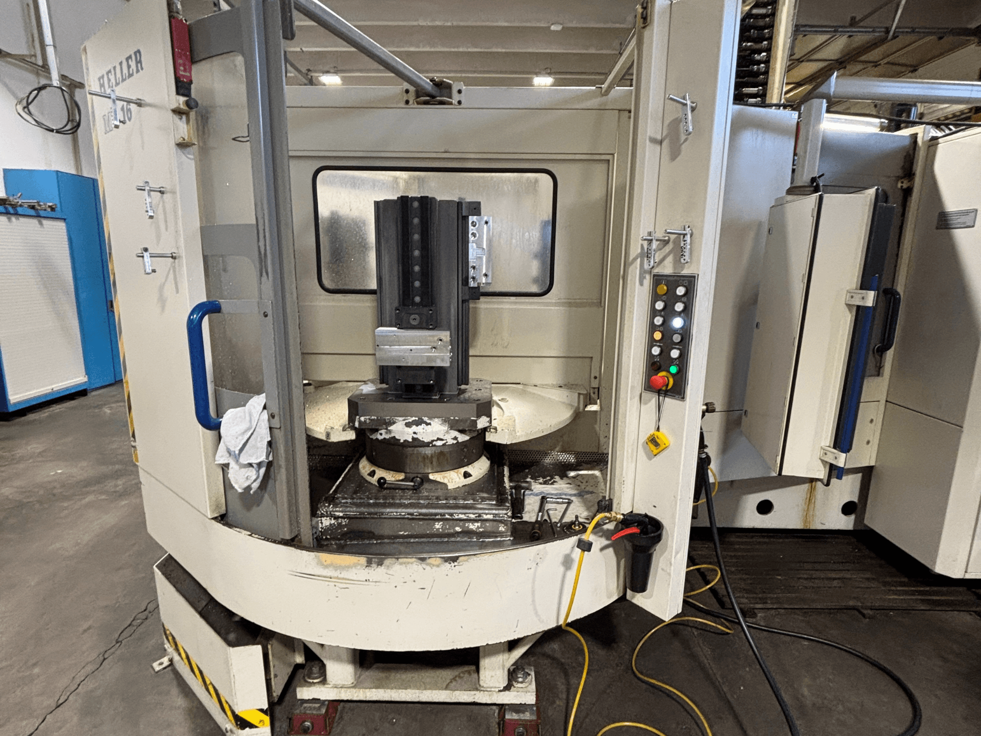 Heller bearbetningscenter, modell vertikal, framifrån med spindel, kontrollpanel och arbetsbord med utrustning monterad.