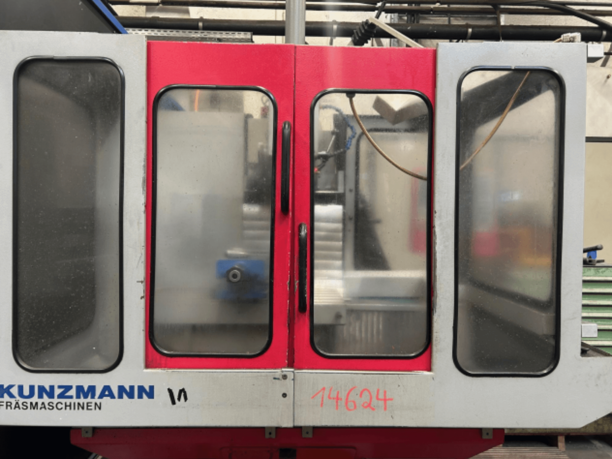 KUNZMANN CNC-maskin framifrån, med röda och grå paneler, med en synlig kontrollpanel och verktygshållare inuti.
