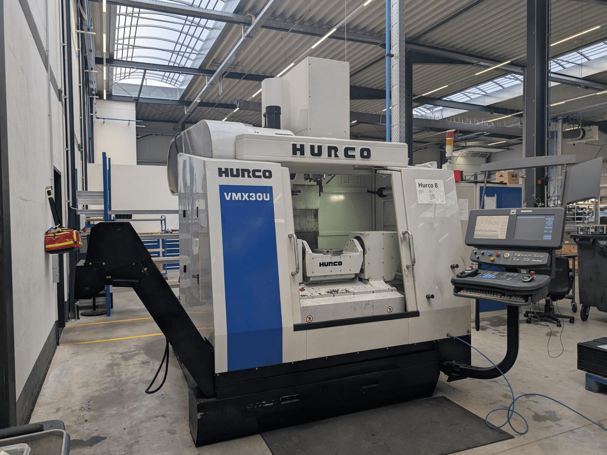Hurco VMX30U CNC-maskin i en verkstad, framifrån, med kontrollpanel med knappar och datadisplay.