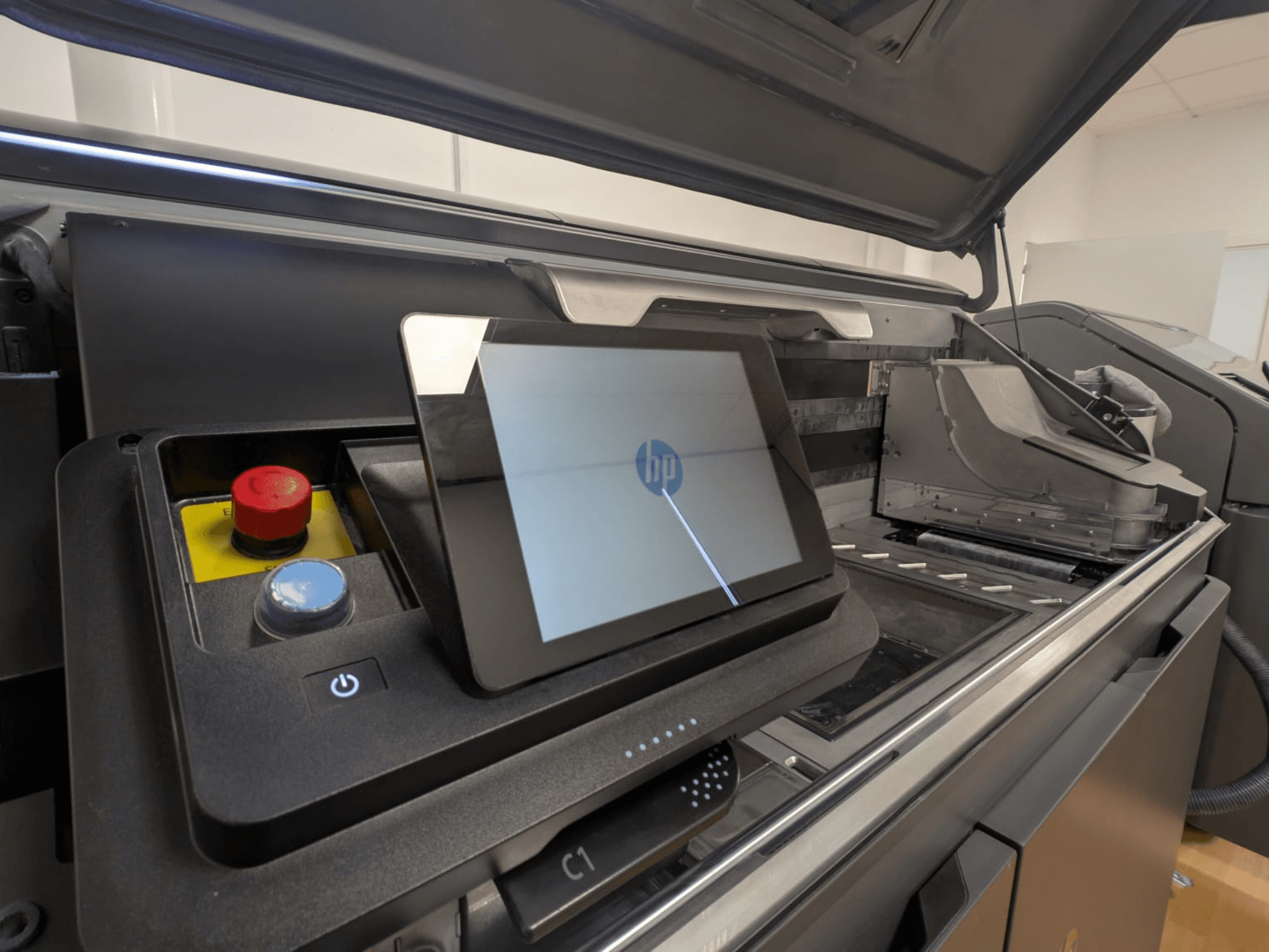 HP-skrivarens kontrollpanel visar en surfplatta, röda och blå knappar samt en sidovy av skrivarens inre komponenter.