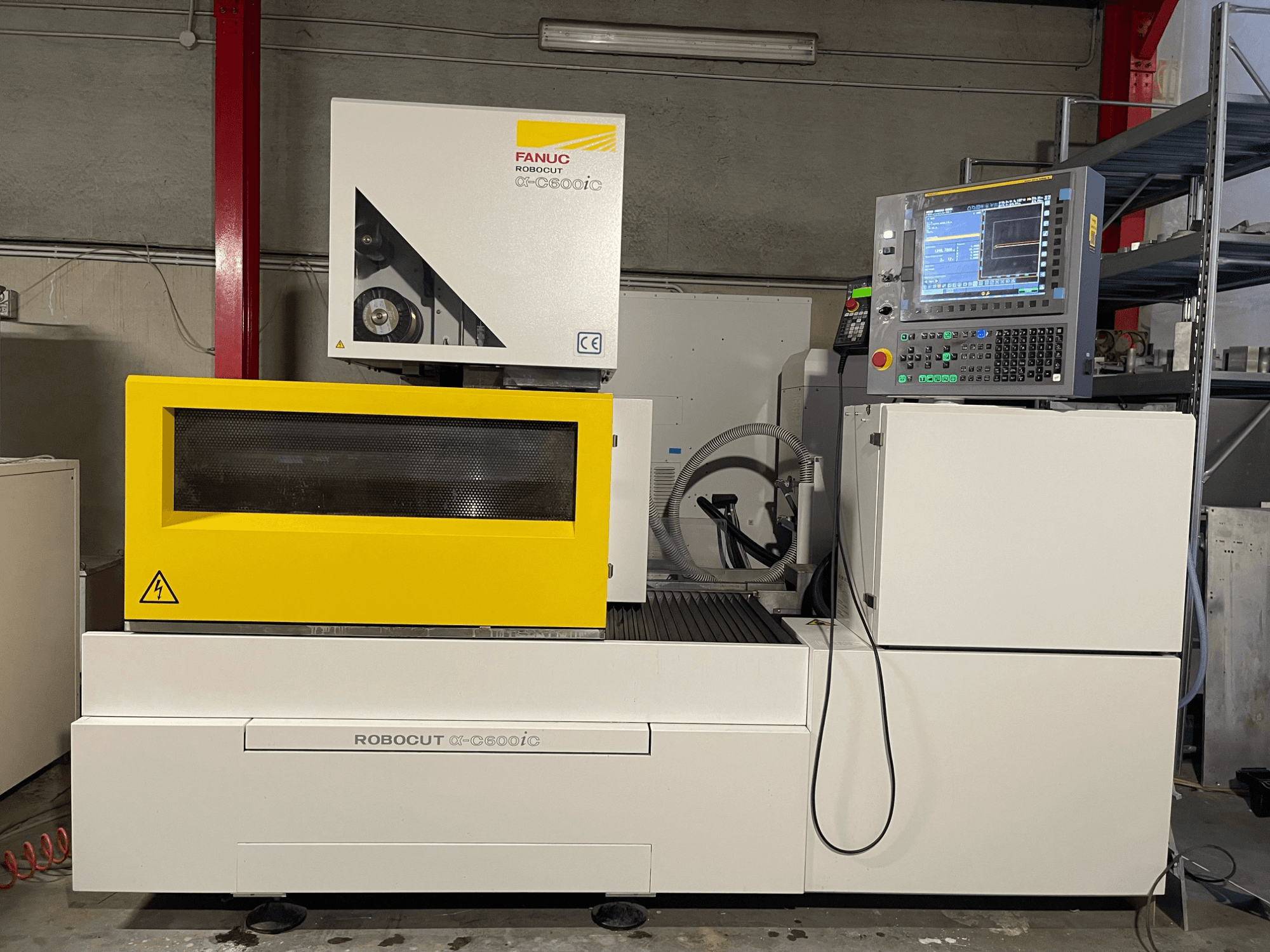 FANUC Robocut α-C600iC, sidovy av CNC-maskin med gult skyddshölje och kontrollpanel som visar kapaciteten för precisionsskärning.