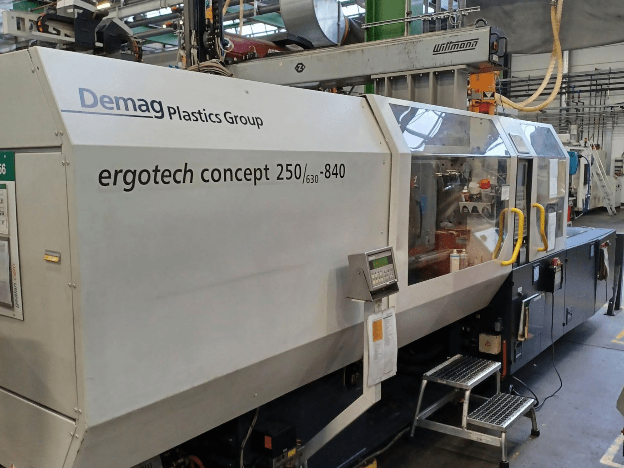 Demag ergotech concept 250/630-840 formsprutningsmaskin, framifrån med digitala reglage och genomskinliga skyddskåpor.