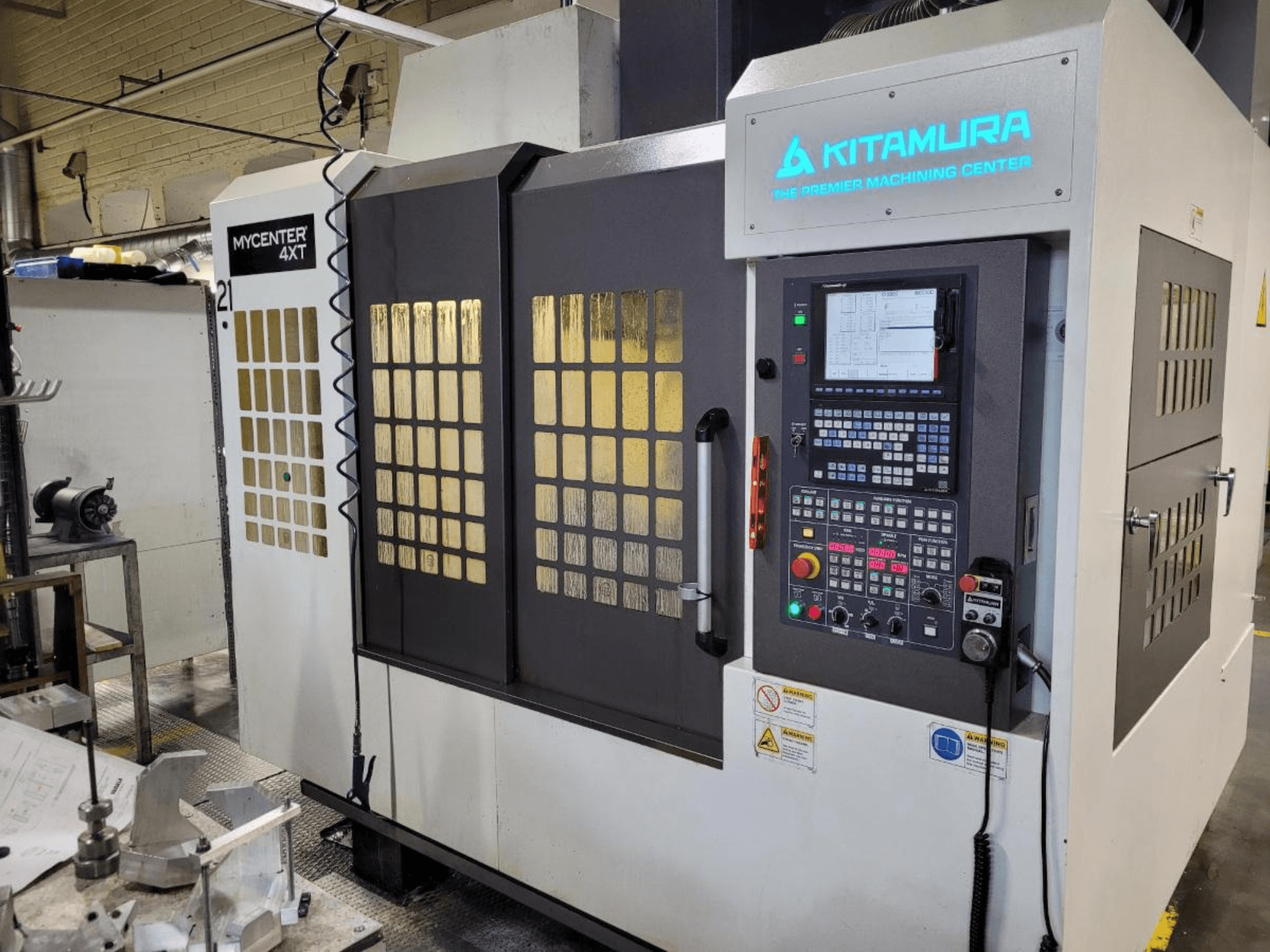 Vertikal vy av en Kitamura Mycenter-4XT fleroperationsmaskin med kontrollpanel och upplyst varumärke.