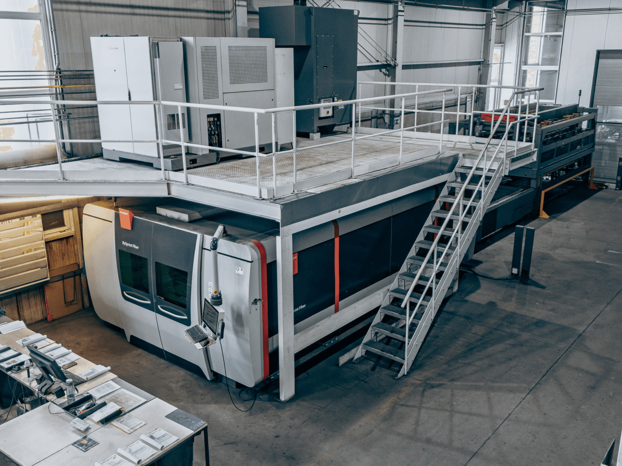 Fiberlaserskärmaskinen Bystronic BySprint Fiber 4020 med ByTransExtended 4020, sedd ovanifrån, med kontrollpanelen och trappan.