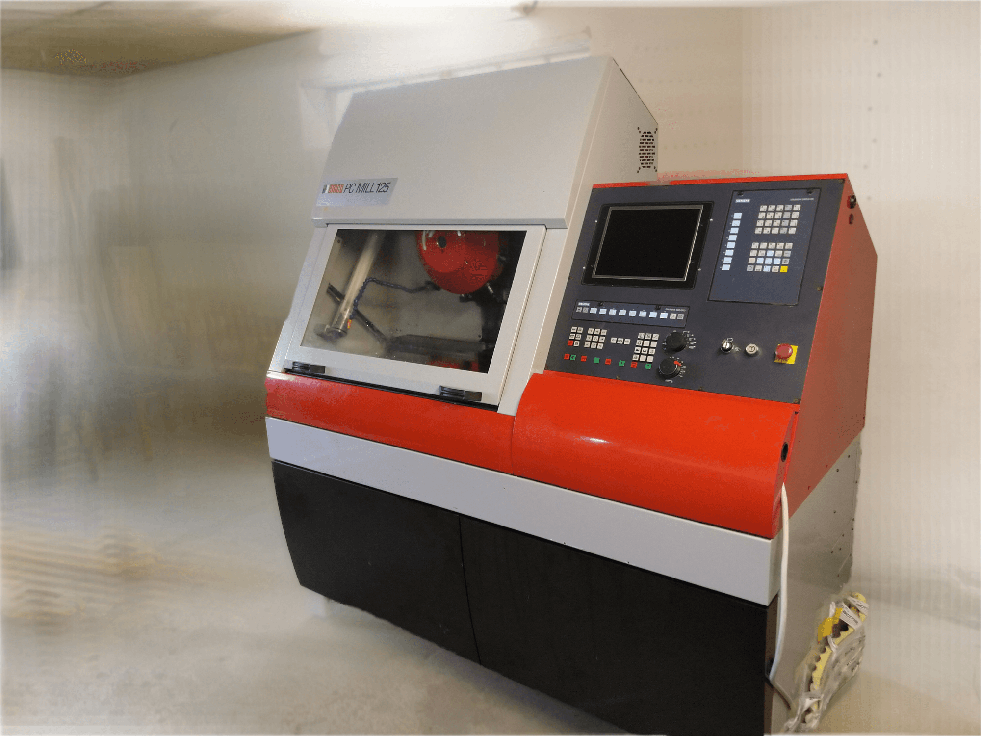 EMCO PC MILL 125 vertikal bearbetningscenter, framifrån med kontrollpanel och synligt bearbetningsområde.