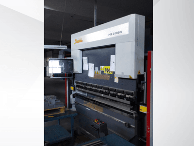 Beyeler HS 21060 kantpress, framifrån, visar reglage, en displayskärm och varningsetiketter i en verkstadsmiljö.
