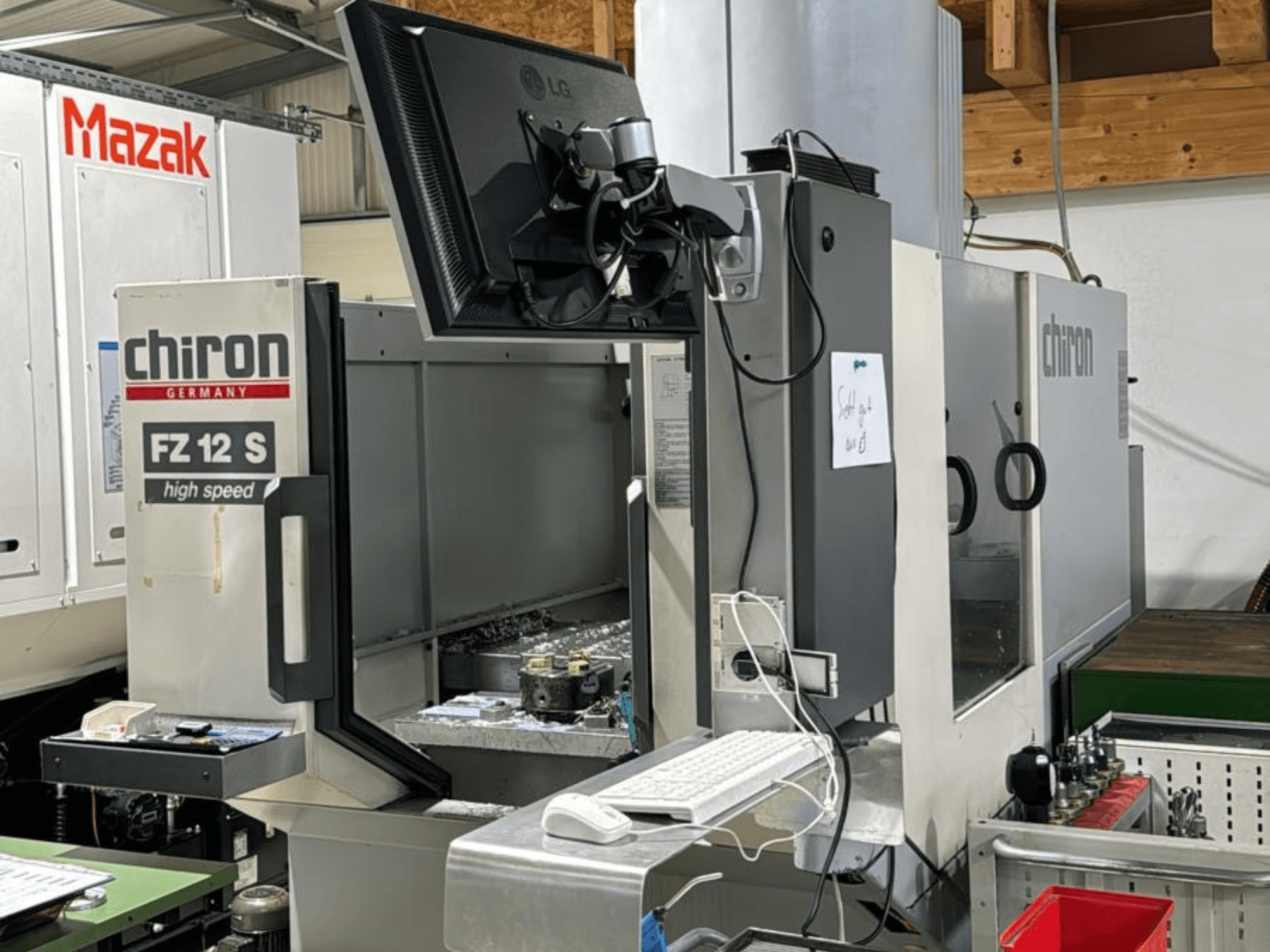 Vertikal vy av CHIRON FZ 12 S höghastighetsbearbetningscenter med kontrollskärm och skräp från bearbetningsprocessen.