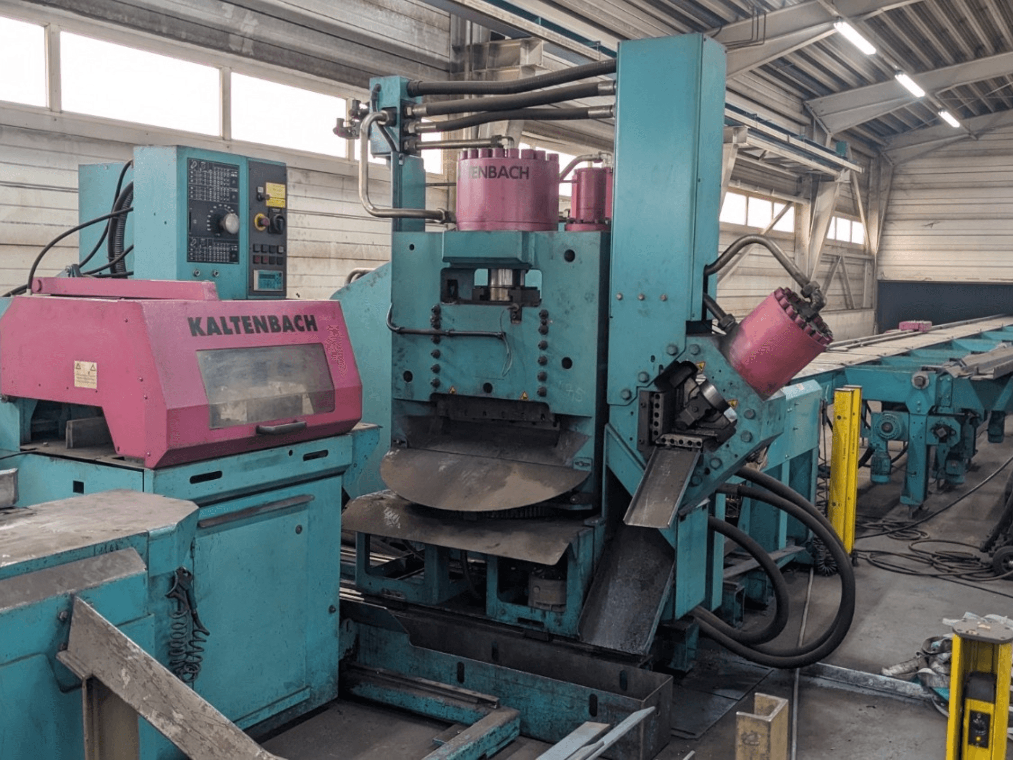 KALTENBACH industrimaskin i färgerna teal och rosa, framifrån, med kontrollpanel och hydrauliska komponenter.