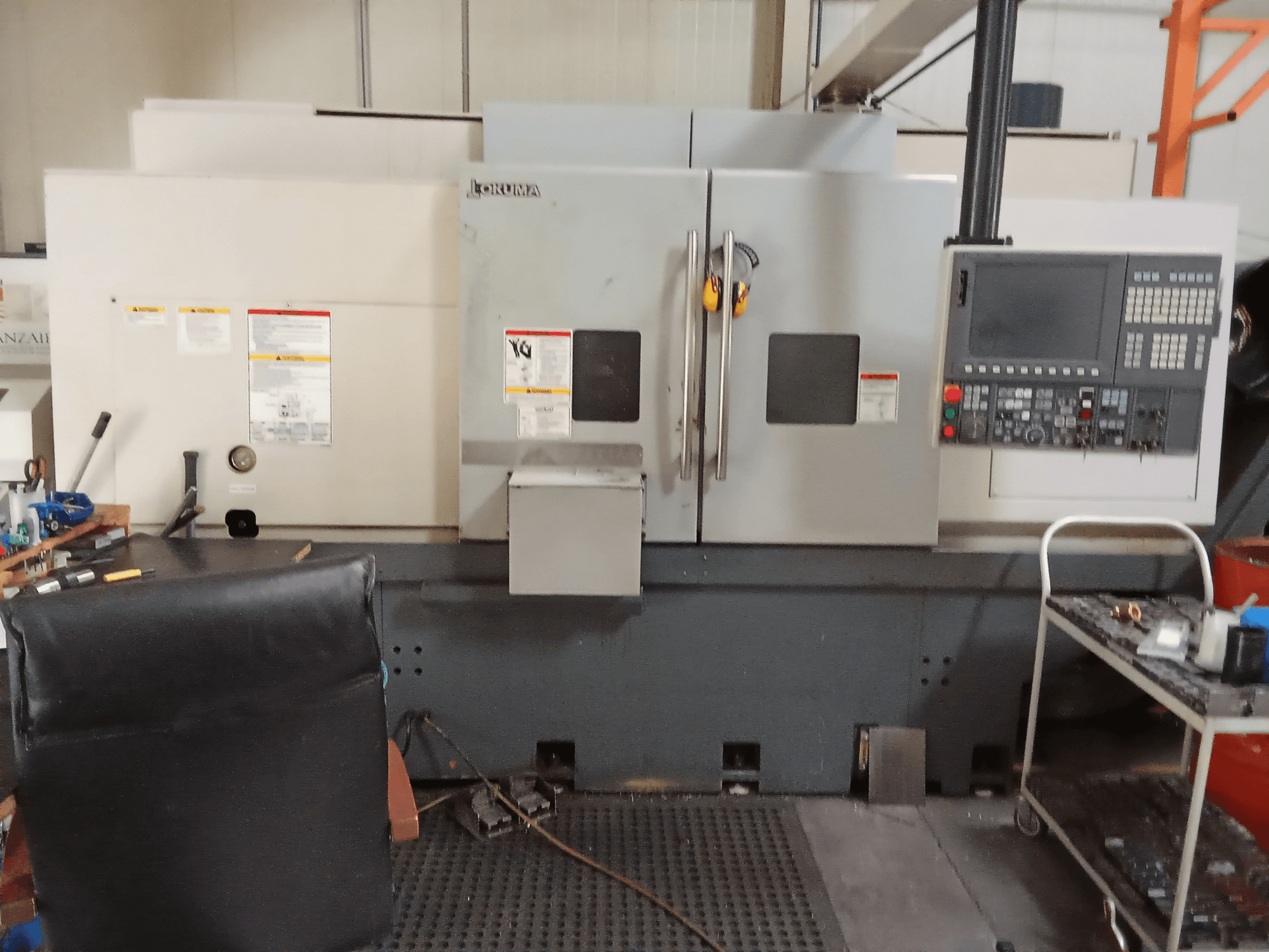 Okuma Genos L300 E-M horisontell svarv framifrån med kontrollpanel och dubbla dörrar i en verkstadsmiljö.