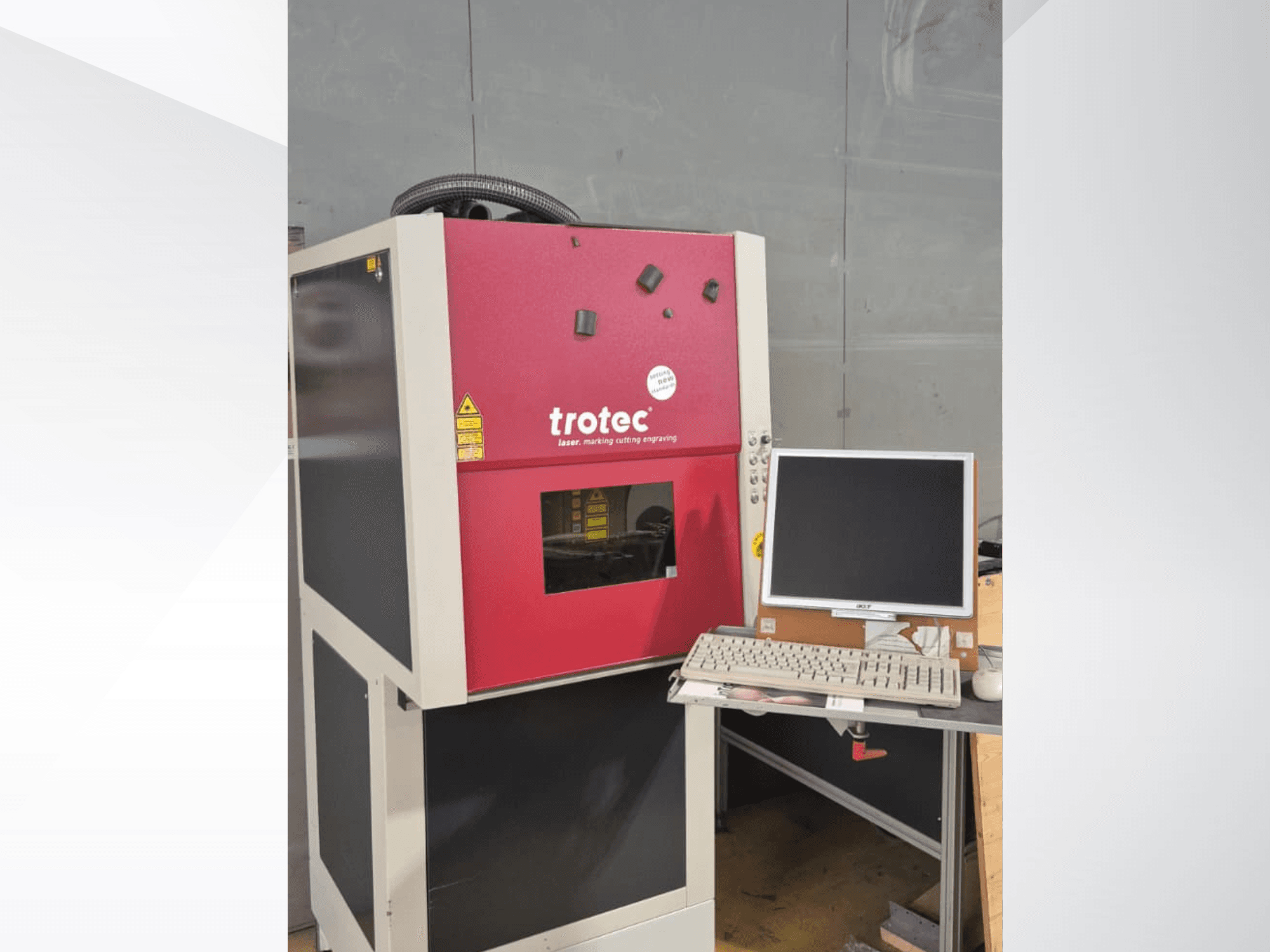 En röd Trotec Laser-Work-Station sedd framifrån, med en bildskärm och ett tangentbord på arbetsstationen.
