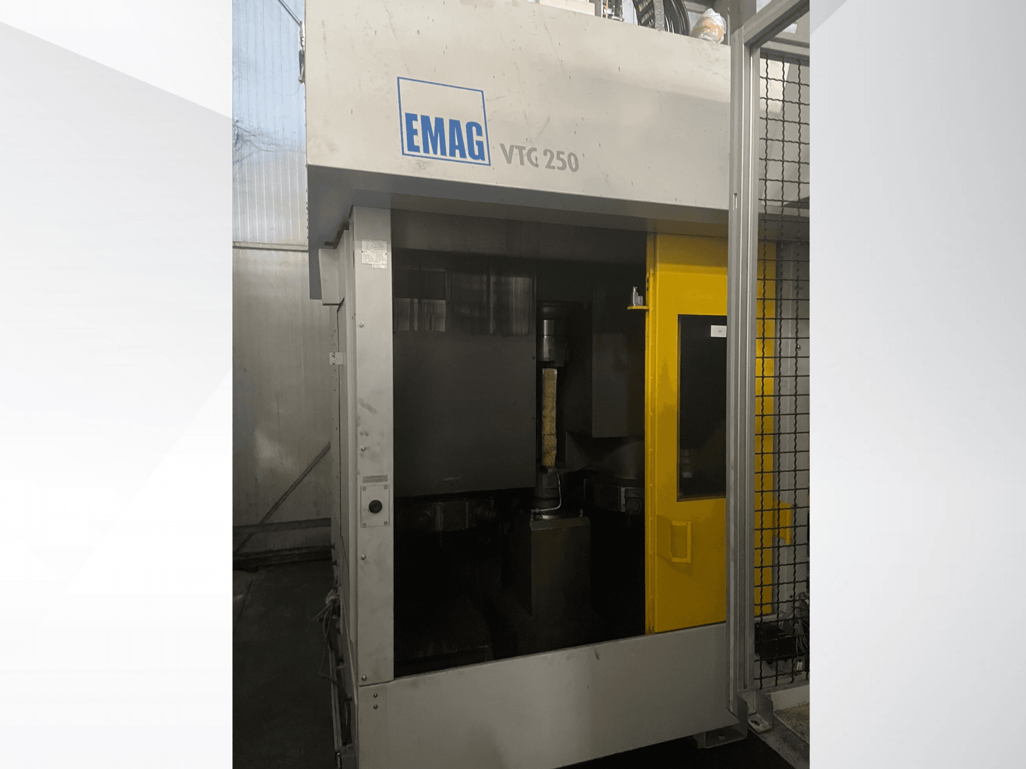 EMAG VTC 250 vertikal fleroperationsmaskin framifrån, med gul dörr och ett synligt skärverktyg inuti kammaren.