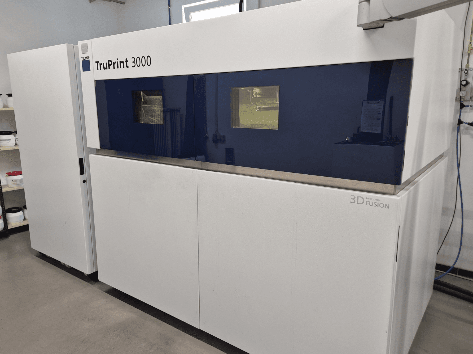 3D-skrivare TruPrint 3000 för metall, framifrån, med design med blå paneler och laserfusionsteknik.