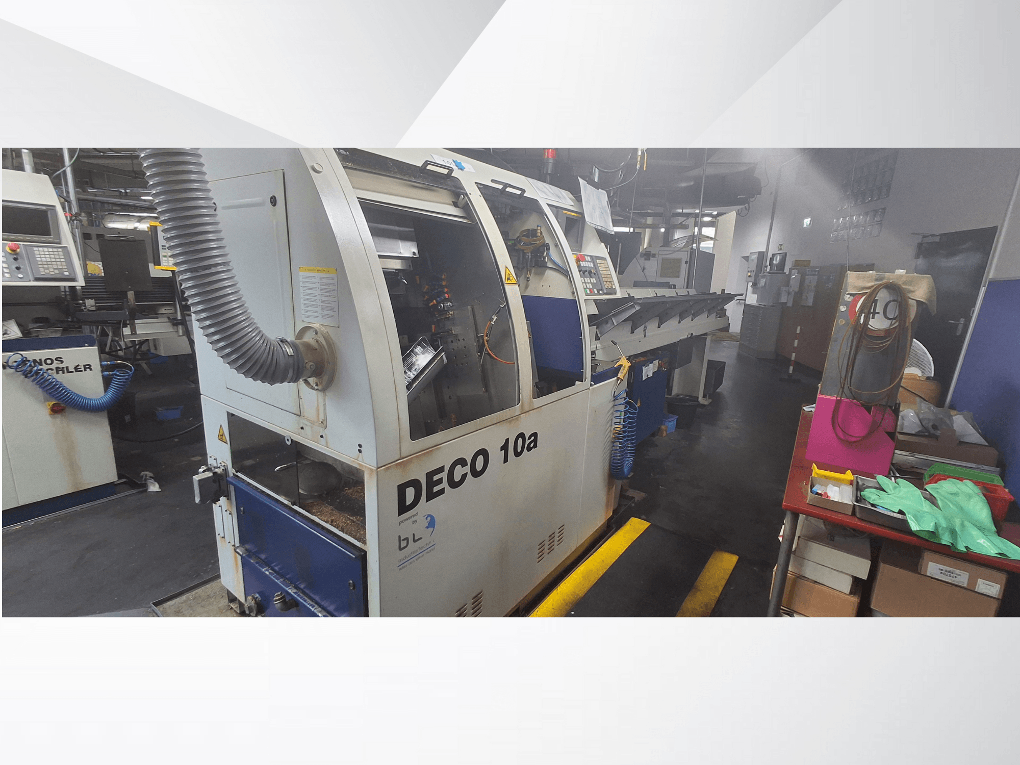 DECO 10a CNC-maskin i en verkstad, framifrån; har en kontrollpanel och dammutsugningssystem, med arbetsbänk i närheten.