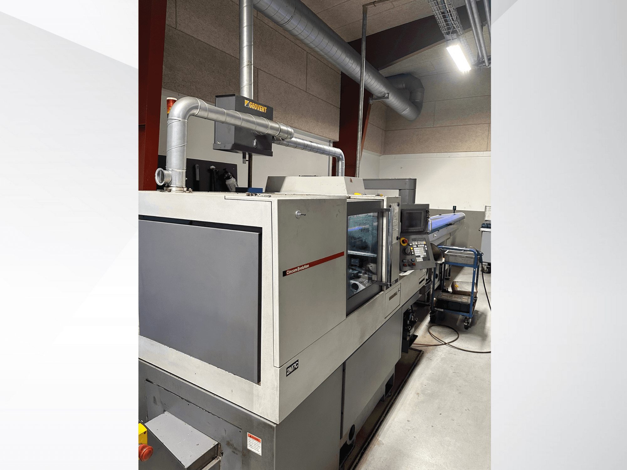 Industrimaskiner från märket MVC, sidovy med kontrollpanel och kanalsystem synliga, placerade i en fabriksmiljö.