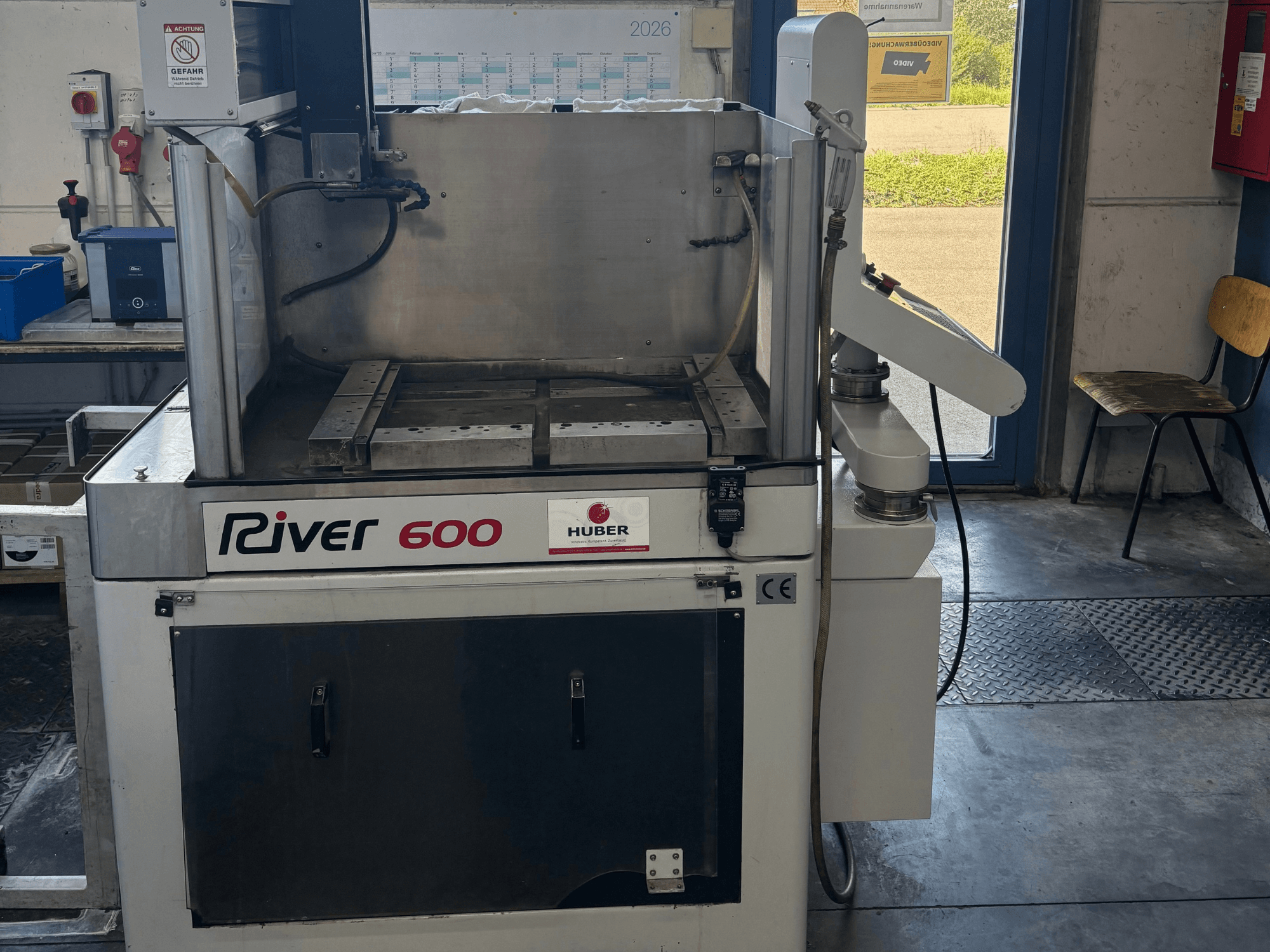 HUBER River 600 CNC-maskin för djupgnistning, framifrån sett, med en delvis öppen arbetskammare och kontrollpanel.