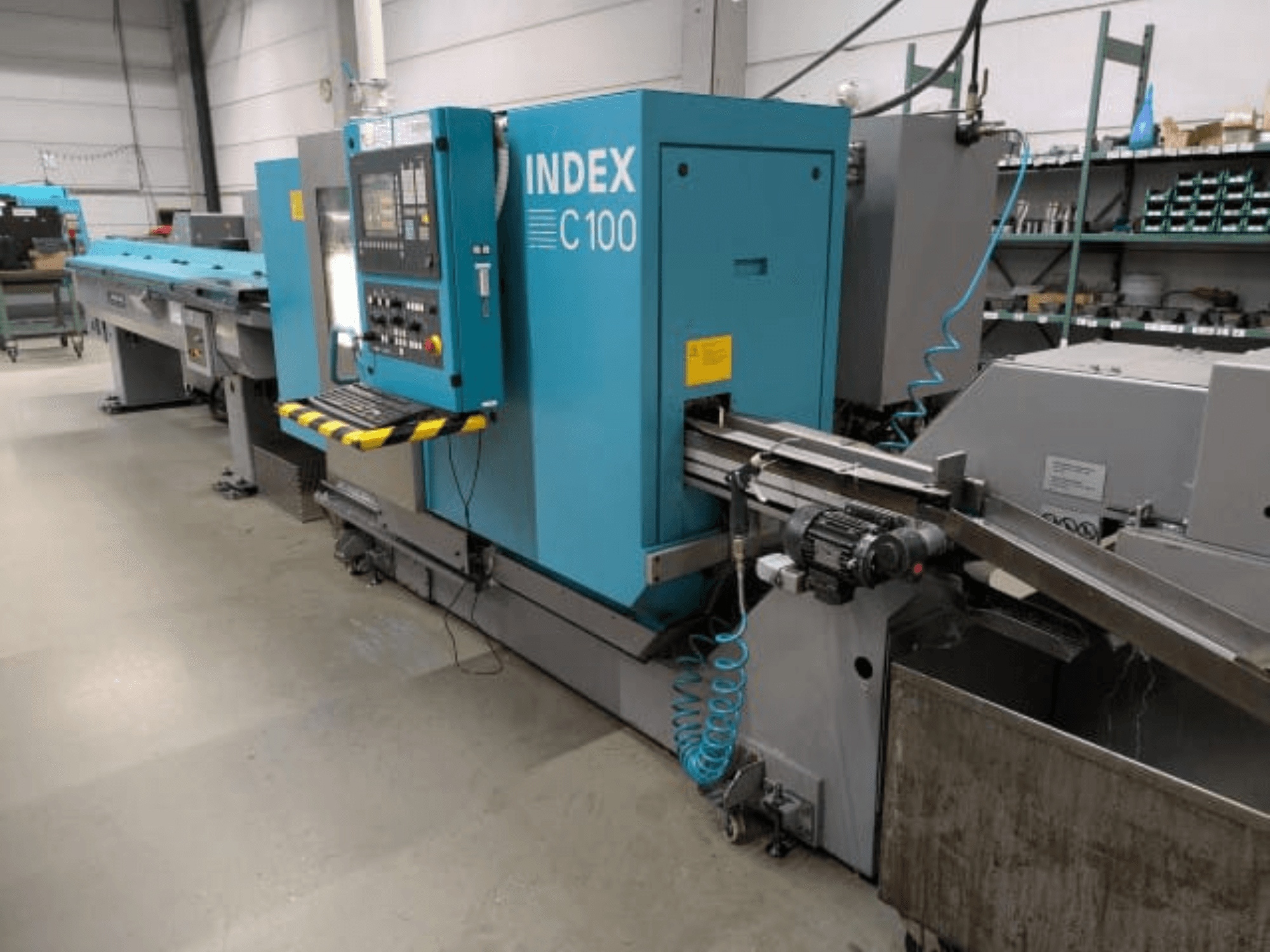 Index C100 horisontell svarv, sidovy; utrustad med kontrollpanel, matningssystem och uppsamlingsbehållare för metallspån.