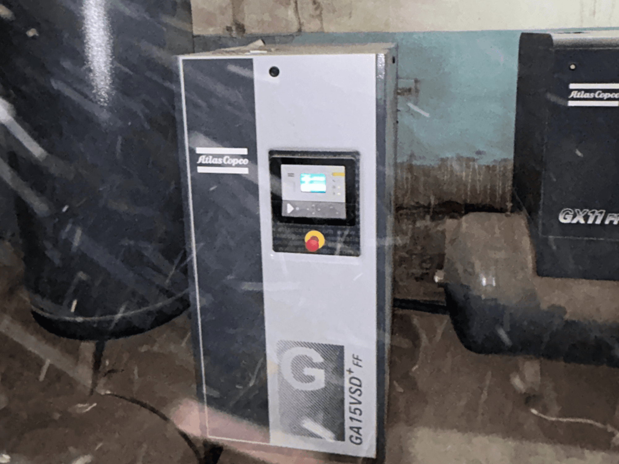 Atlas Copco GA15VSD+FF luftkompressor, framifrån, med kontrollpanel med display och röd nödstoppsknapp.