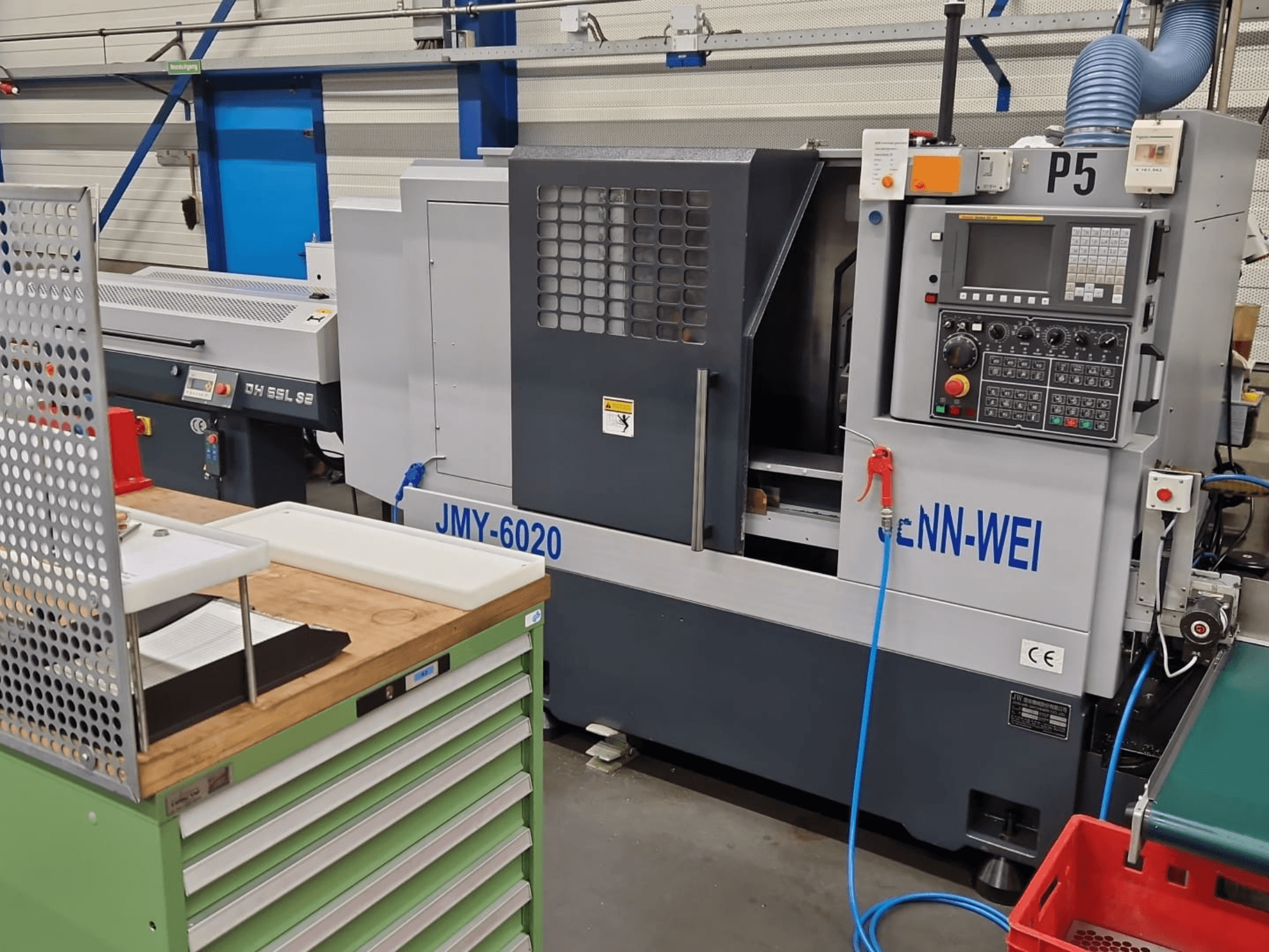 CNC-svarvmaskin, modell JMY-6020 från cNN-WEI, sedd framifrån. Med kontrollpanel, nödstopp och kylvätskeledning.