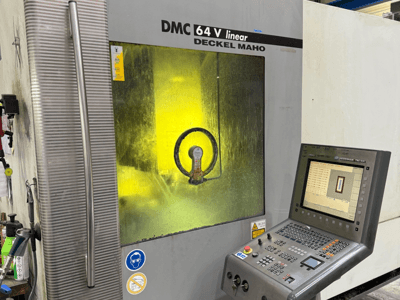 DMC 64 V linear av Deckel Maho, maskinens framsida med kontrollpanel och gult tonat fönster som visar de inre mekanismerna.