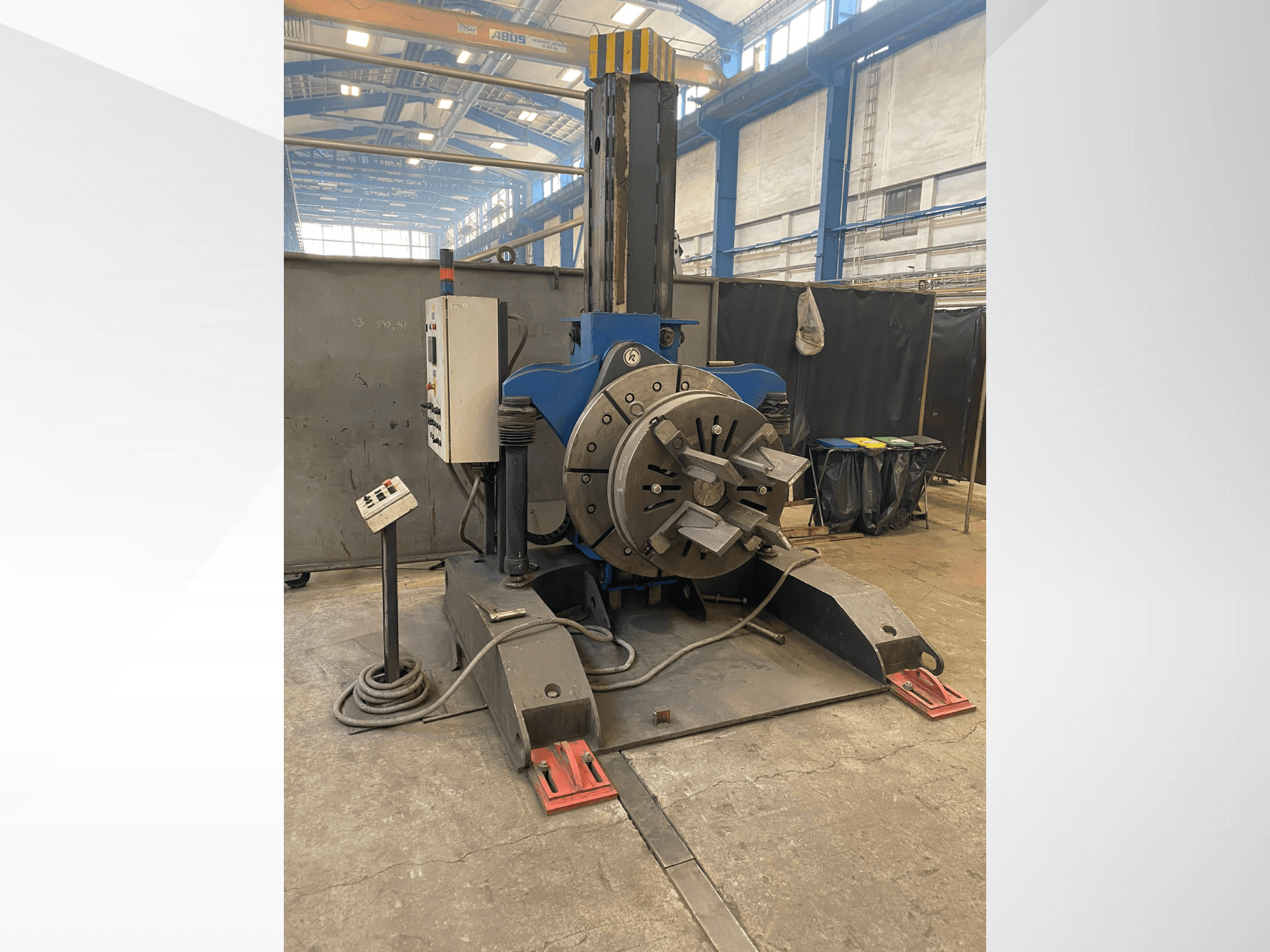 Blå industrisvarv med runt roterande huvud och kontrollpanel, sidovy, i en verkstadsmiljö.