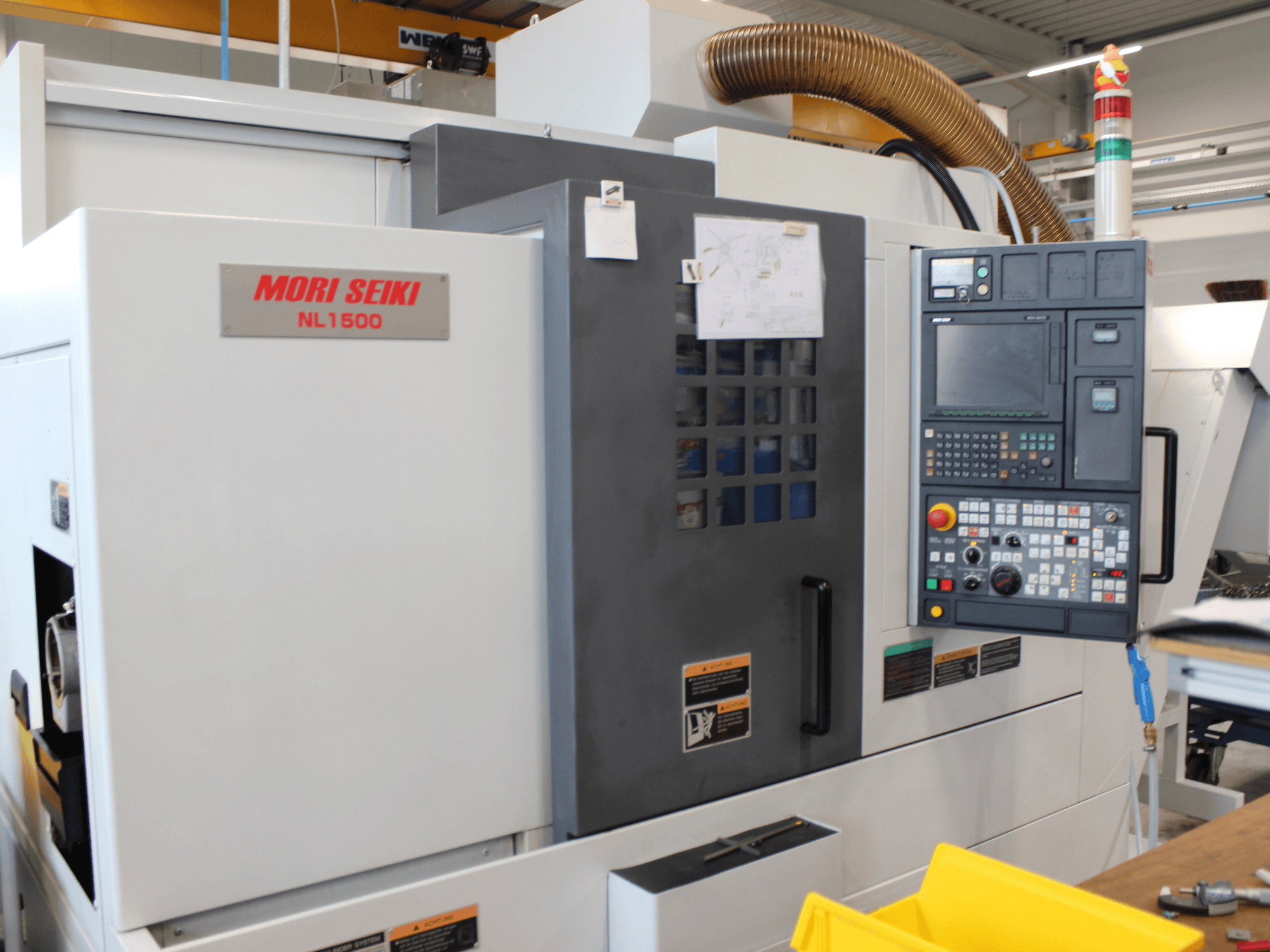 MORI SEIKI NL 1500 SY svarv- och fräscenter sett från sidan, med kontrollpanel, säkerhetsmärkningar och kylsystem.