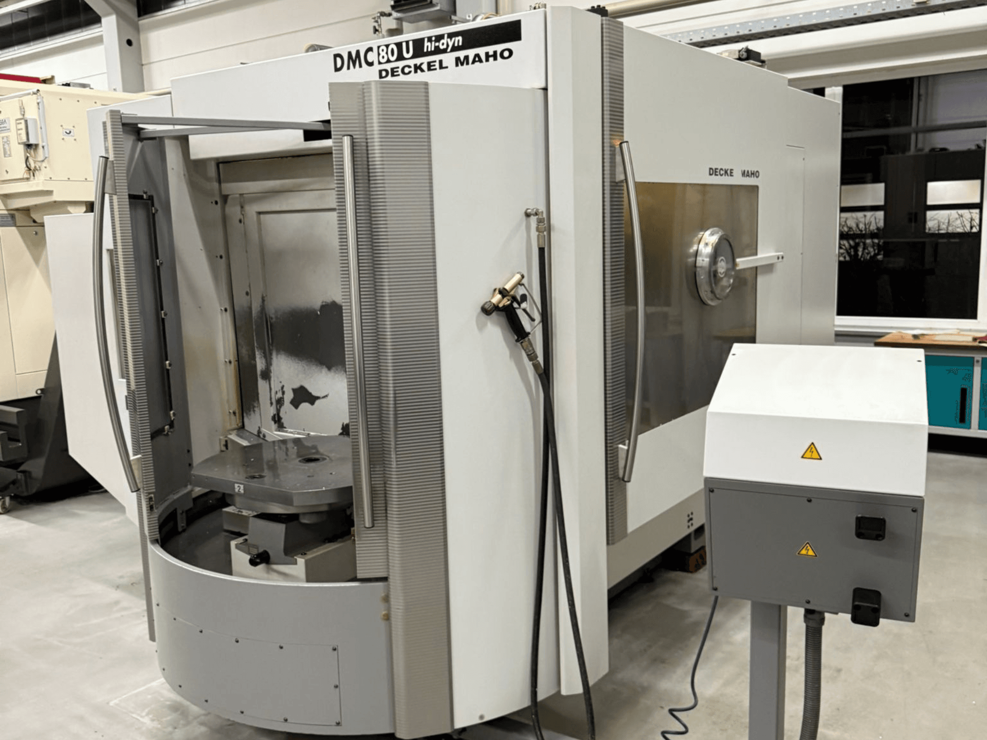 Frontvy av en Deckel Maho DMC 80 U CNC-fräsmaskin med hög hastighet, med öppen åtkomstdörr och kontrollpanel på sidan.
