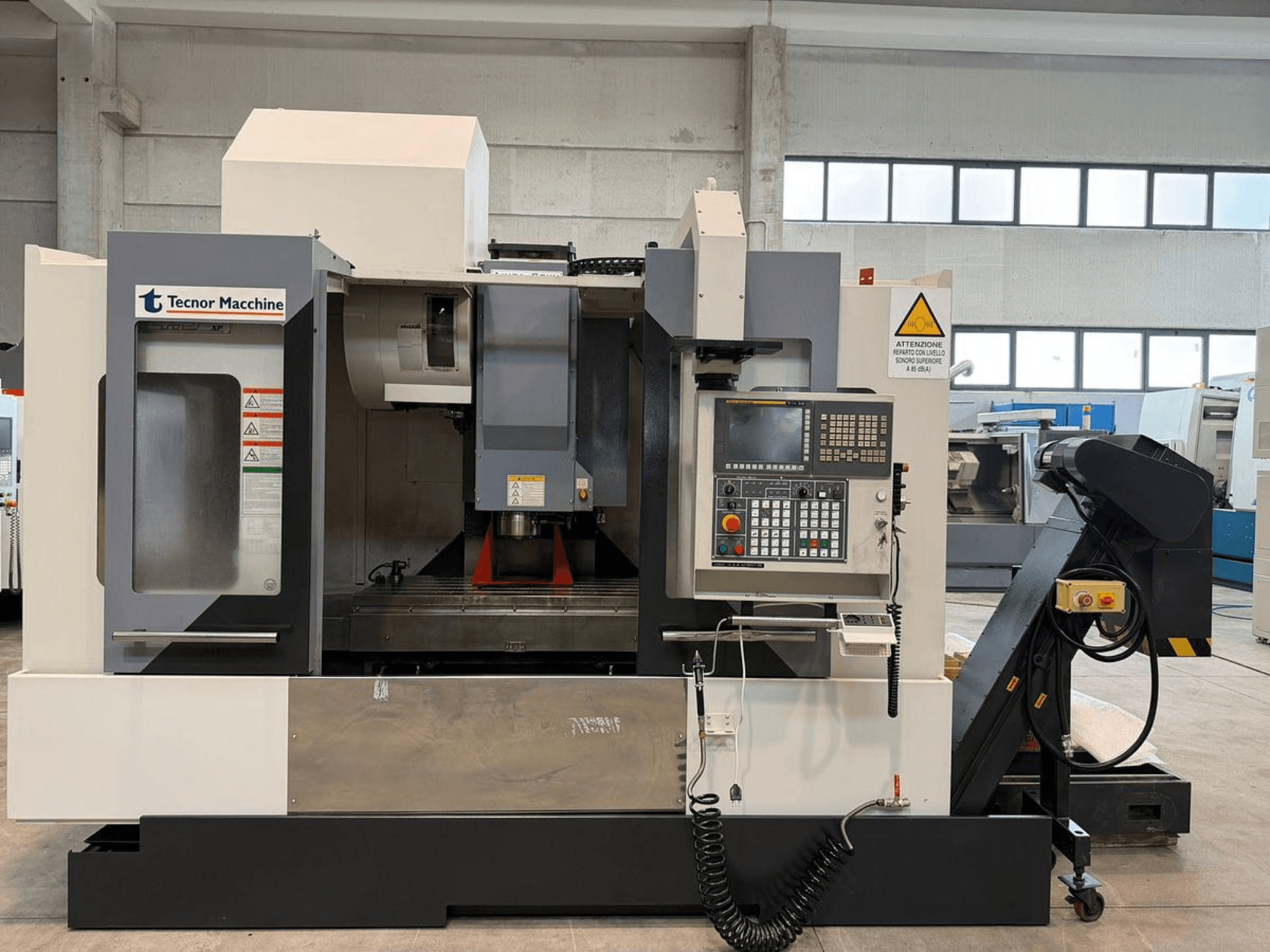 Tecnor Machine CNC-fräsmaskin, framifrån, har kontrollpanel med knappar, varningsetiketter och verktygshållare.