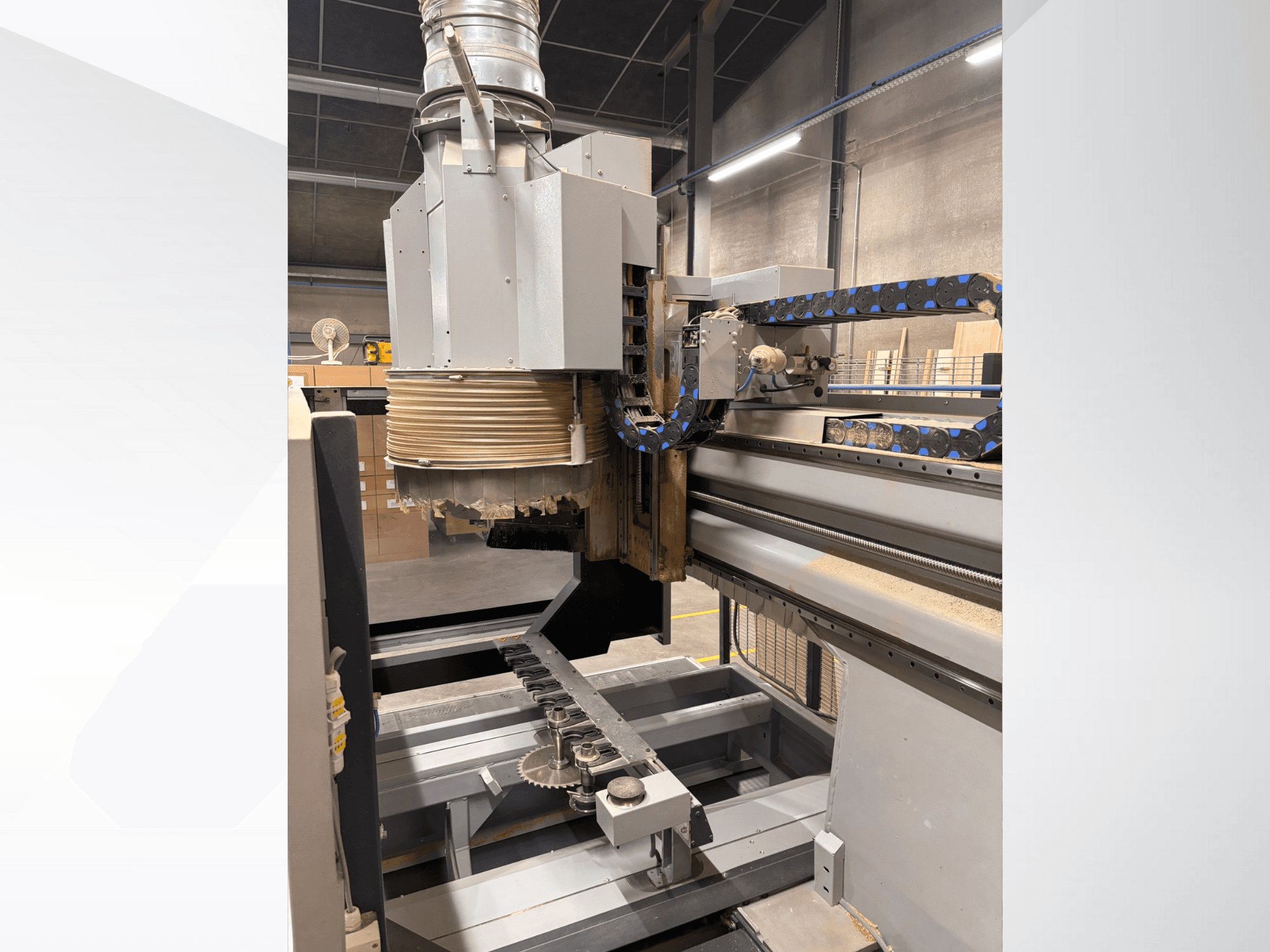 CNC-fräsmaskin med stor spindel och transportör, sidovy, som visar verktyg och maskinkomponenter för träbearbetning.