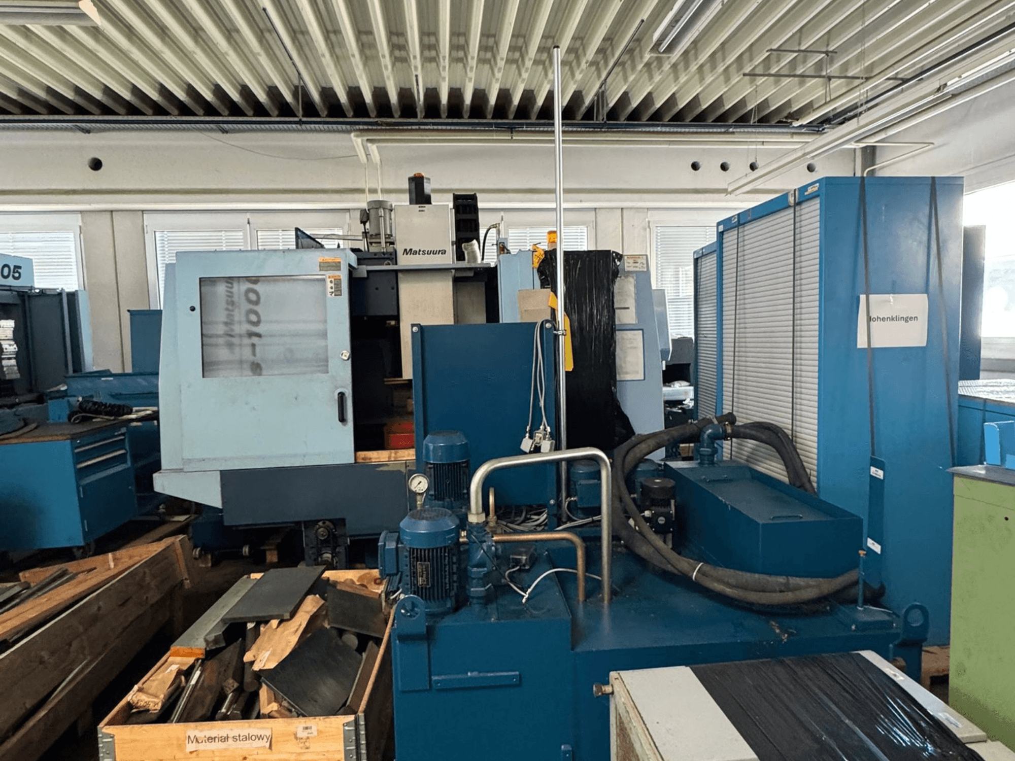 Framifrånbild av det vertikala bearbetningscentret Matsuura Vplus 1000/40, som visar styrsystem, motorer och den omgivande verkstadsmiljön.