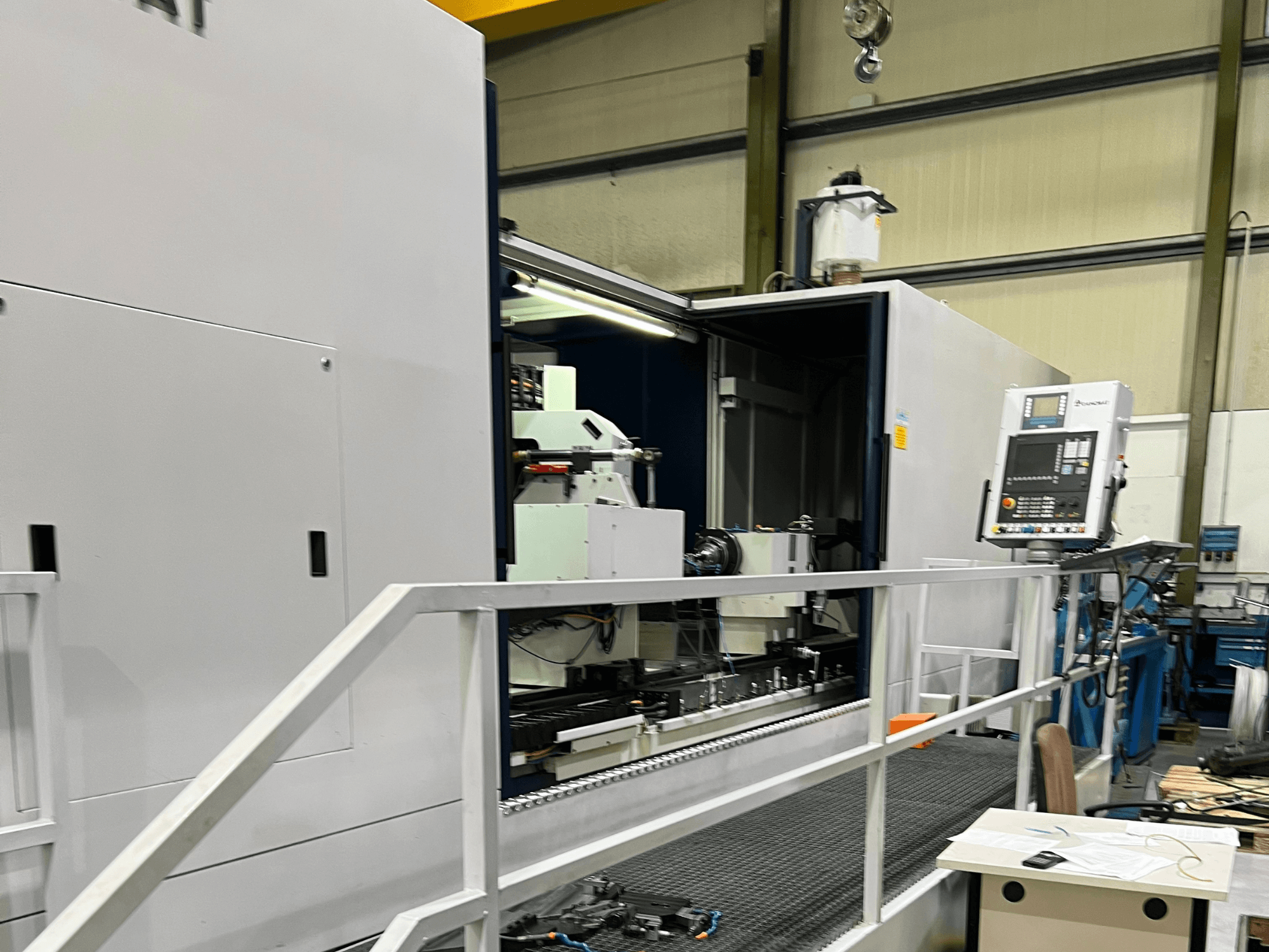 CNC-bearbetningscenter med öppen sidovy som visar reglage, verktygshållare och huvudkomponent inuti. Varumärkesdetaljer inte synliga.