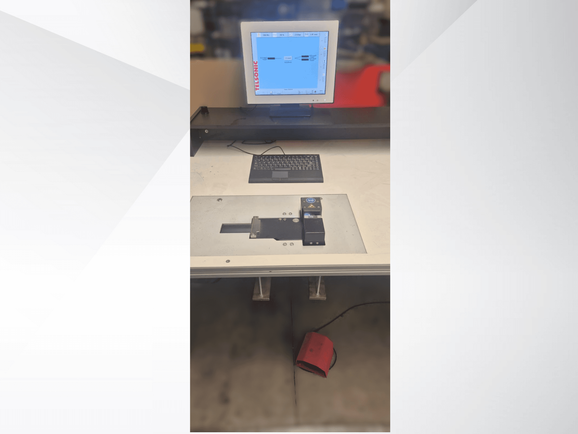 En vy uppifrån och ned av en teststation med datorskärm, tangentbord och kontrollpanel med en knapp och en grön lampa.