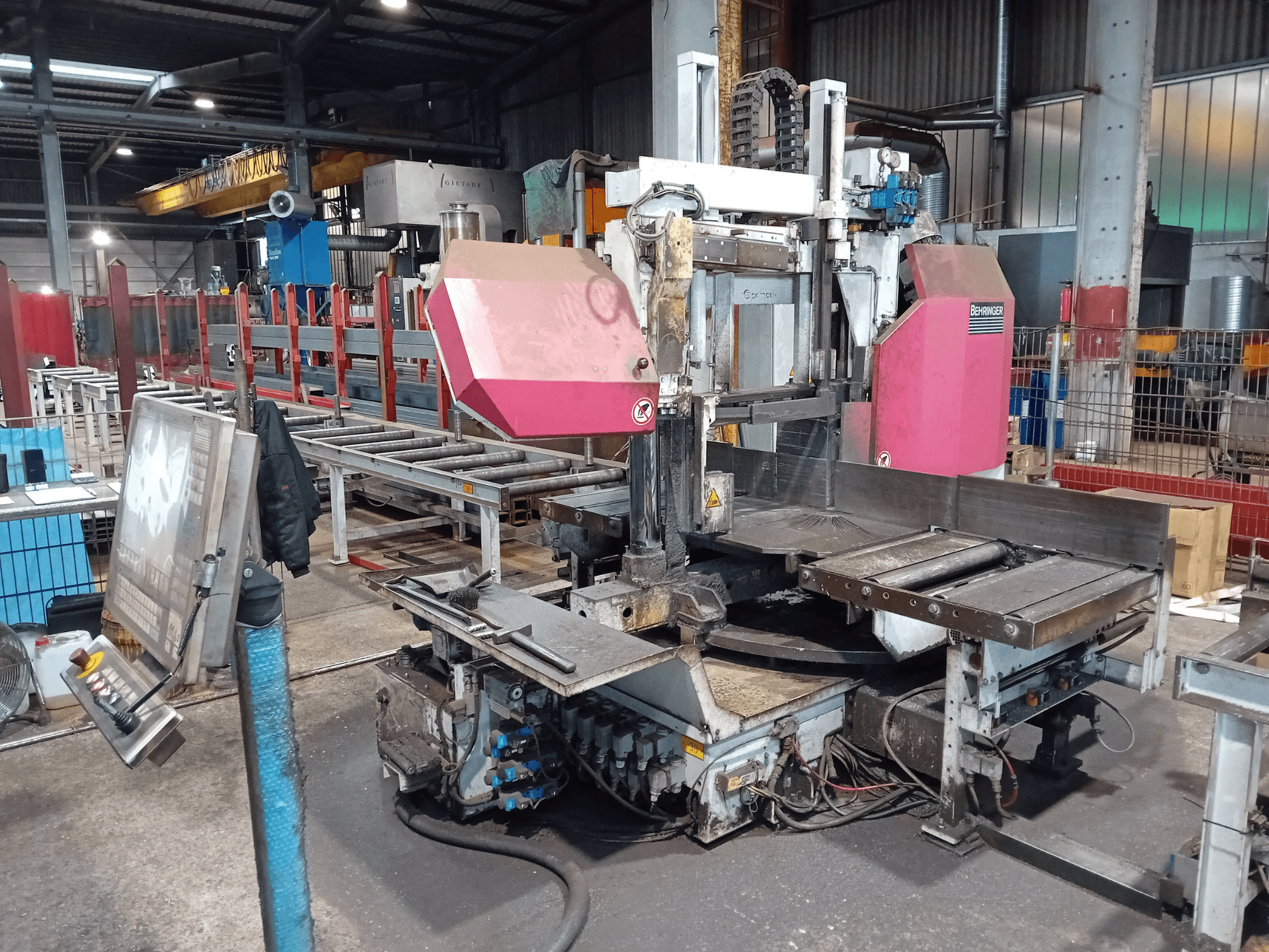 Behringer bandsågsmaskin i en fabrik, framifrån, med stort kapblad och kontrollpanel med knappar.