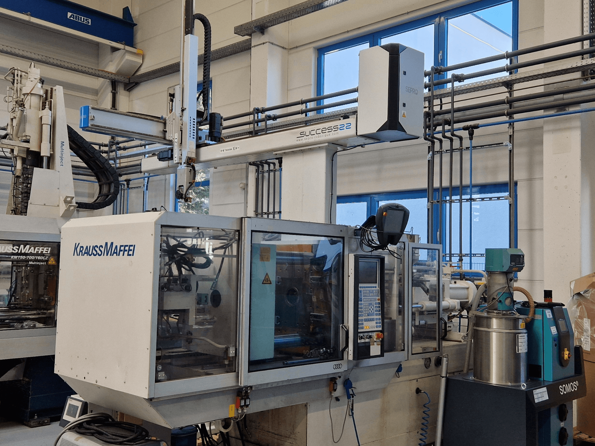 KraussMaffei Success 22 formsprutningsmaskin med kontrollpanel, sedd framifrån i en fabriksmiljö.