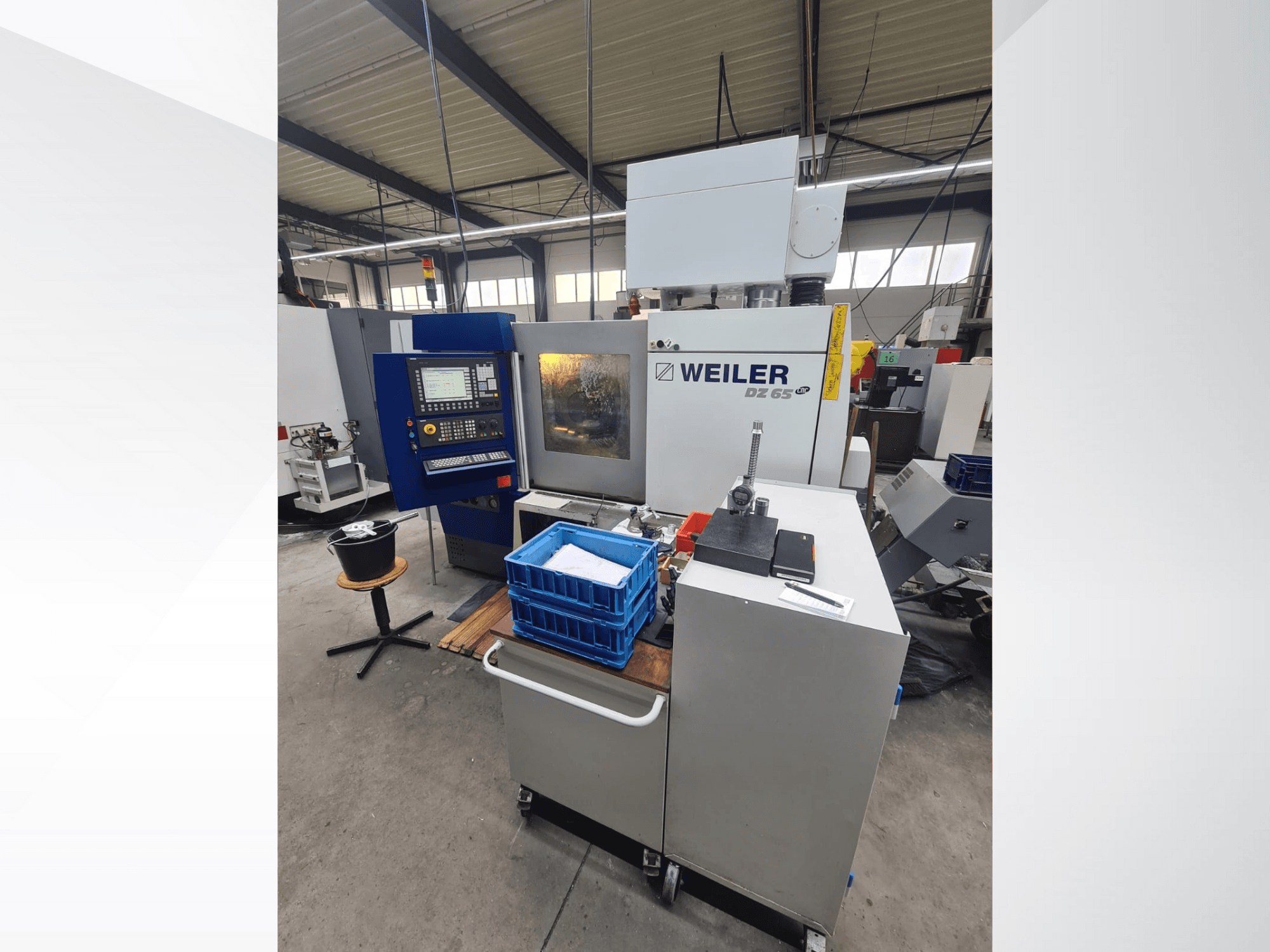 Weiler DZ 65 CNC-maskin i en verkstad, framifrån med kontrollpanel, verktyg och blå förvaringsfack synliga.