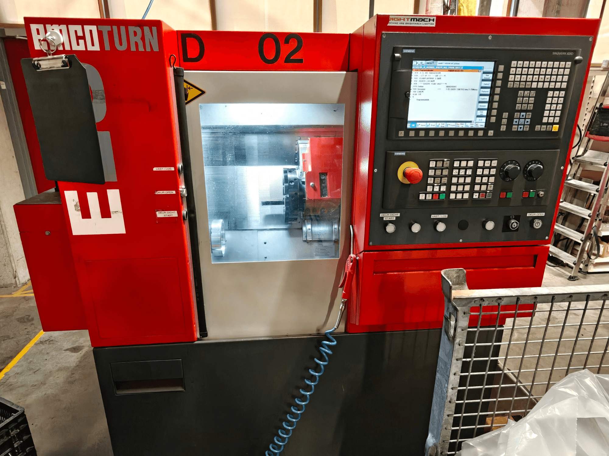 Framifrånvy av den horisontella svarven EMCO TURN E25, där man ser kontrollpanelen, skärmen och bearbetningsområdet.