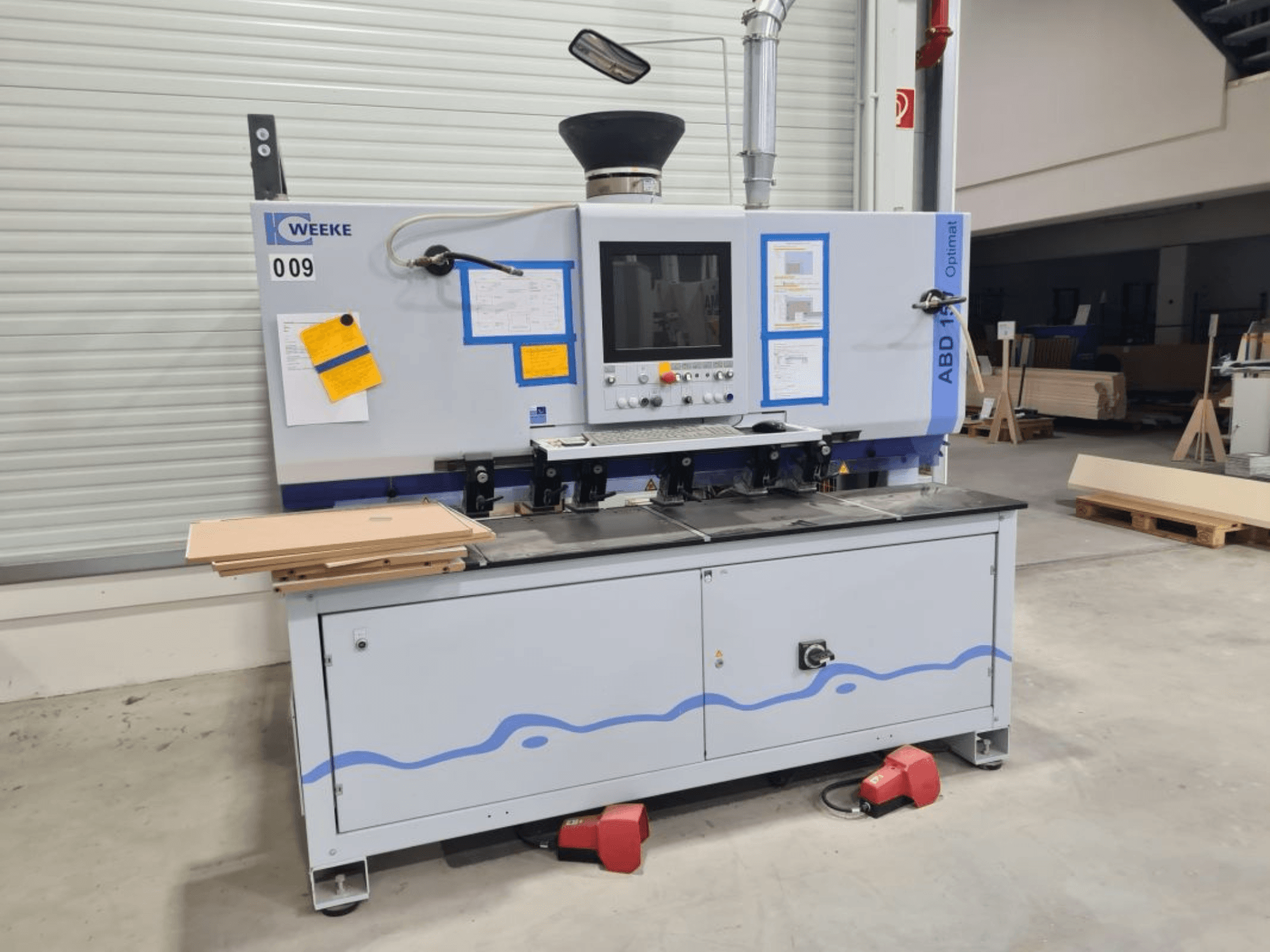 HOMAG WEEKE OPTIMAT ABD150 flerspindlig borrmaskin, framifrån, visar reglage och staplade träpaneler.