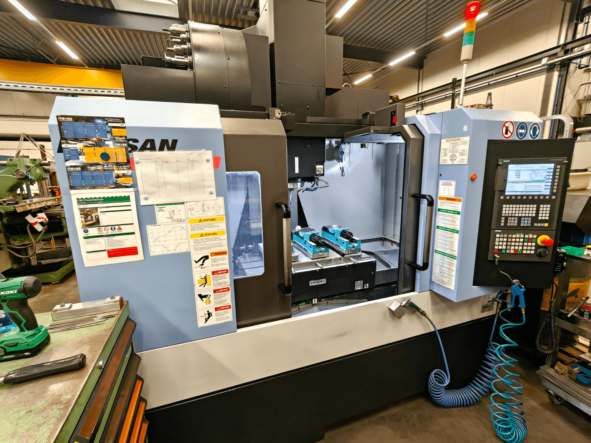 DOOSAN DNM 400 II vertikal fleroperationsmaskin i en verkstad, med reglage, verktygshållare och säkerhetsskyltar, framifrån.